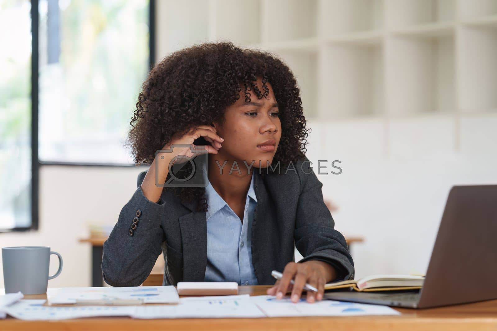 Royalty free image of Portrait thoughtful confused young african american businesswoman looking at laptop. Stress while reading news, report or email. Online problem, finance mistake, troubleshooting. by itchaznong
