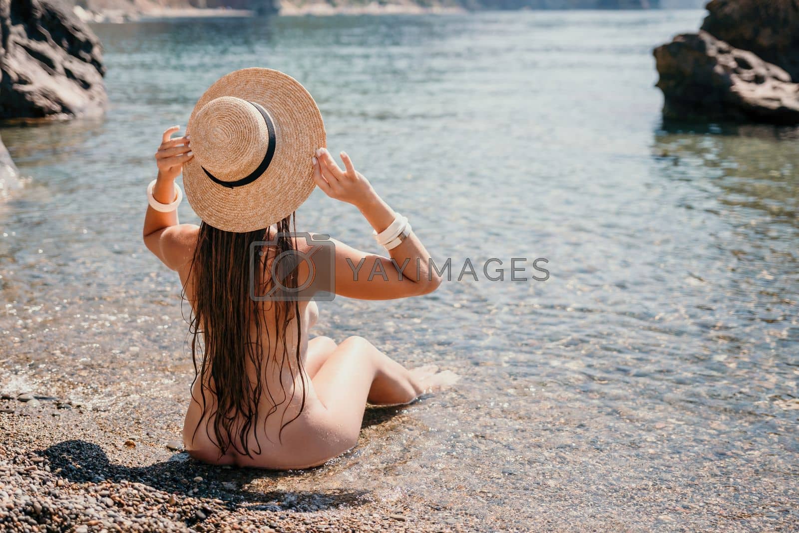 Royalty free image of Woman travel sea. Happy tourist in hat enjoy taking picture outdoors for memories. Woman traveler posing on the beach at sea surrounded by volcanic mountains, sharing travel adventure journey by panophotograph