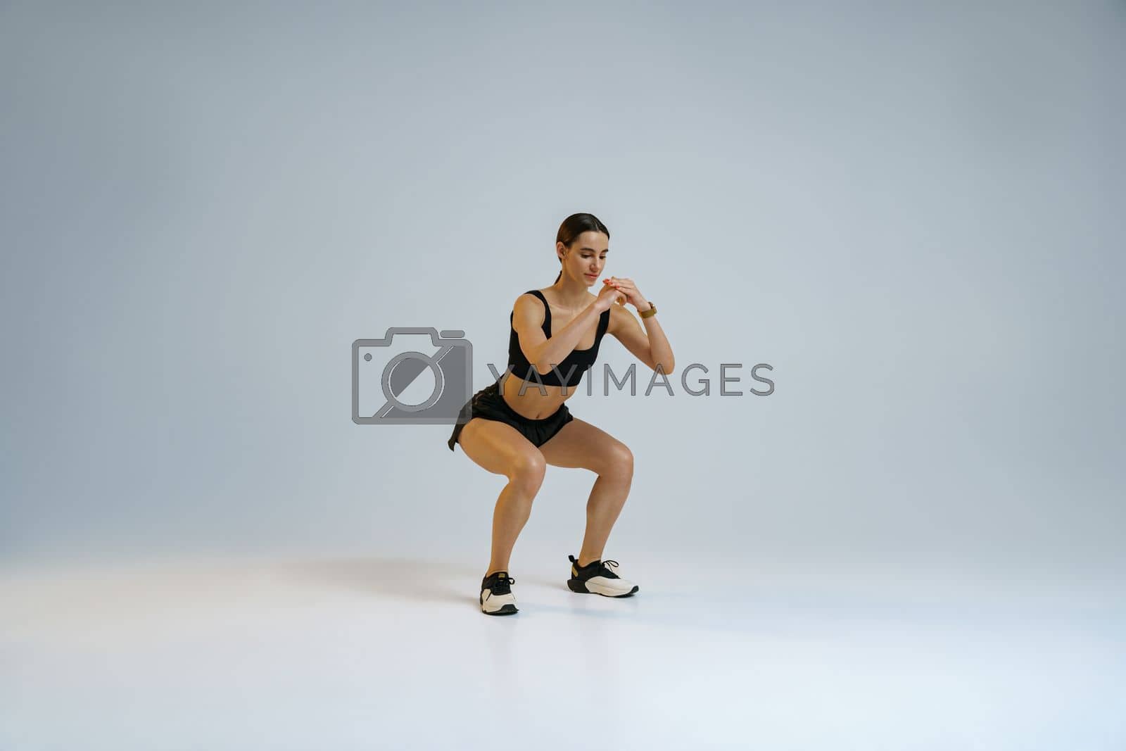 Royalty free image of Fitness woman doing deep squat exercise on studio background. Workout Concept by Yaroslav_astakhov
