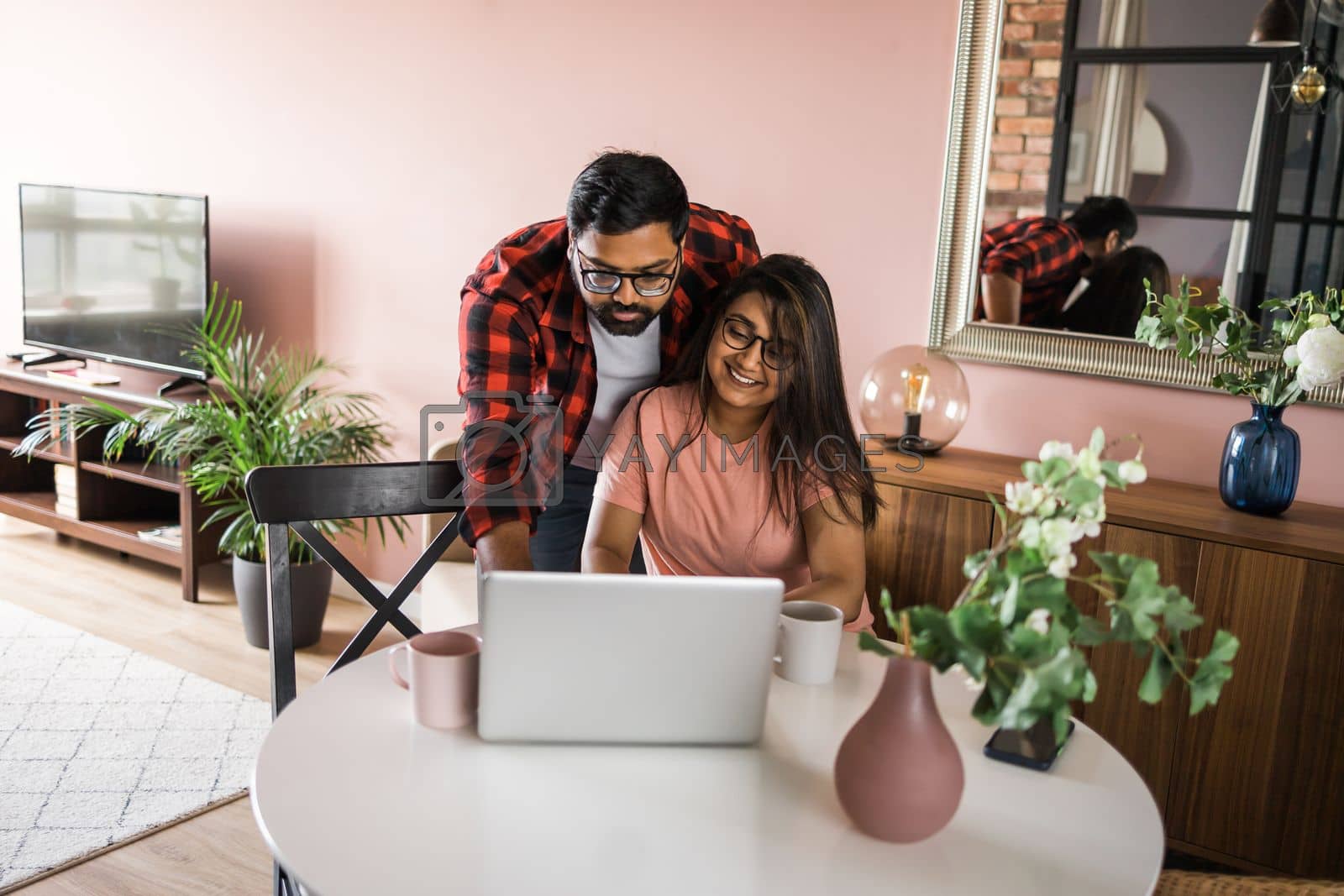 Royalty free image of technology remote job and lifestyle concept - happy indian man and woman in glasses with laptop computer working at home office by Satura86