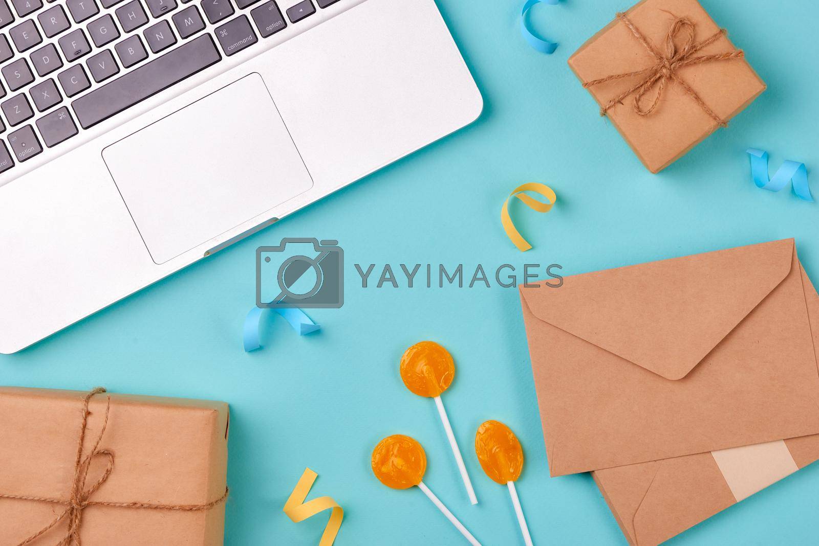 Celebration envelope, birthday party things and laptop on a yellow background
