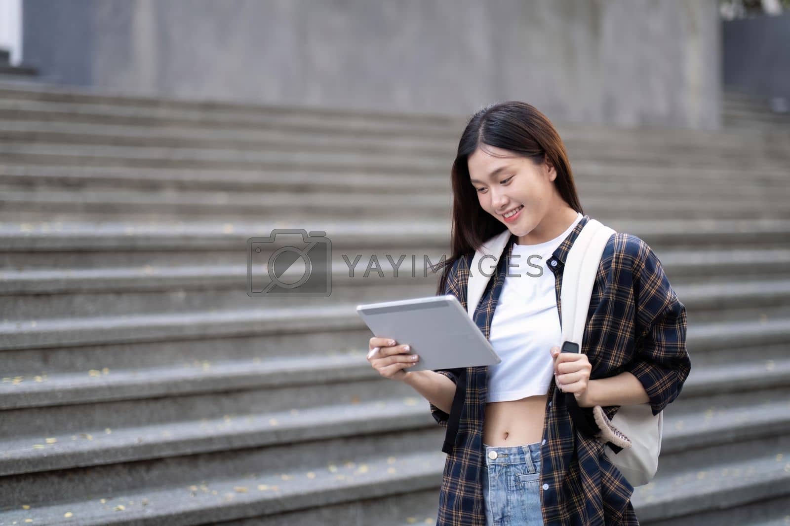 Royalty free image of Asian female college student with her laptop in front of the campus building by nateemee