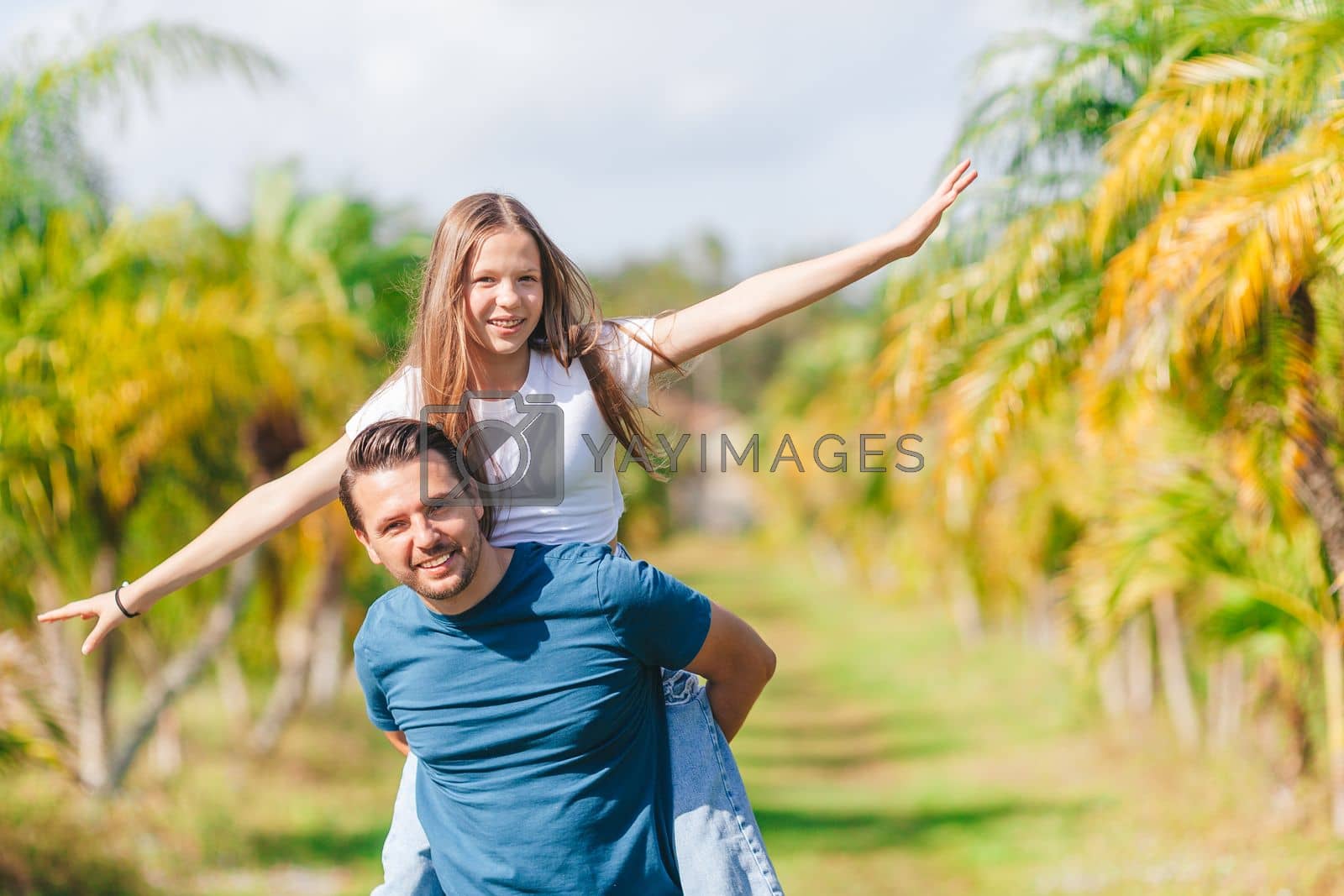 Royalty free image of Family of daughter and father having fun among palm trees on vacation. Family vacation by travnikovstudio