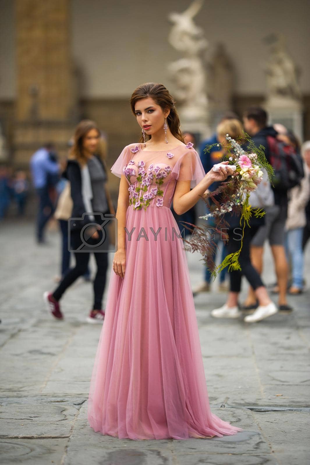 Royalty free image of A bride in a pink dress with a bouquet stands in the center of the Old City of Florence in Italy by Lobachad