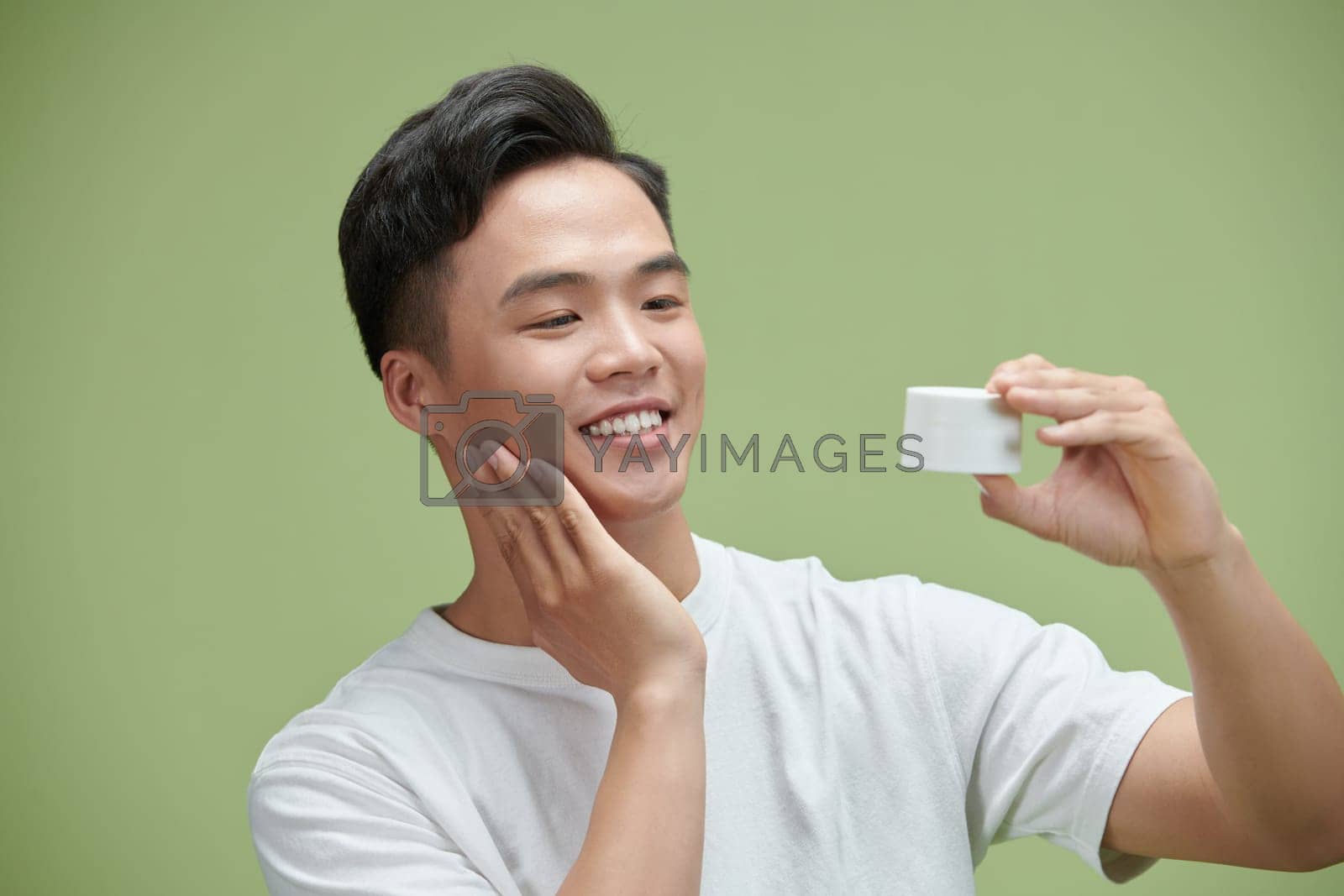 Royalty free image of Portrait of young Asian man with cosmetics bottle by makidotvn