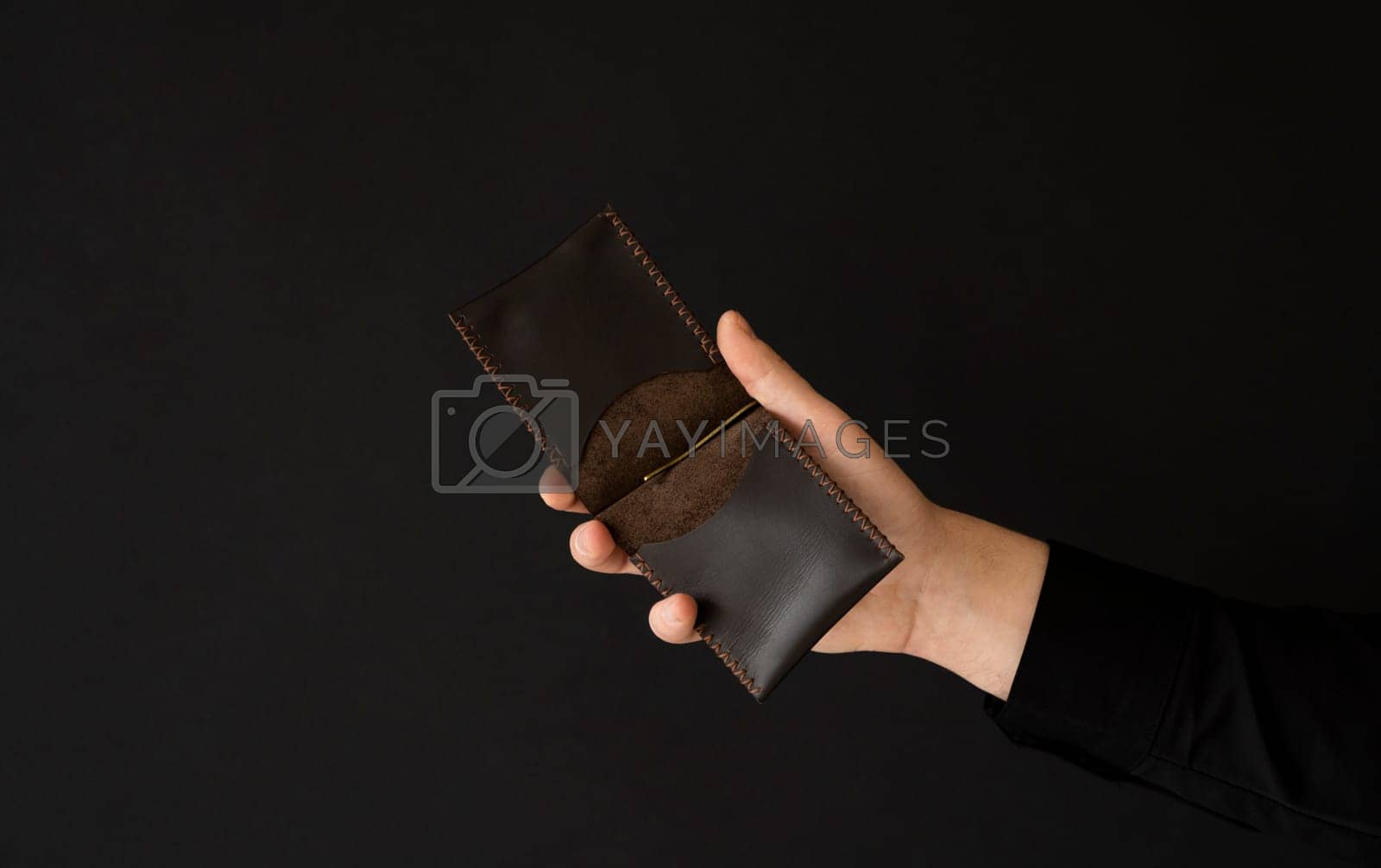 Royalty free image of Brown empty men's business handmade leather card holder in a man's hand. by vovsht