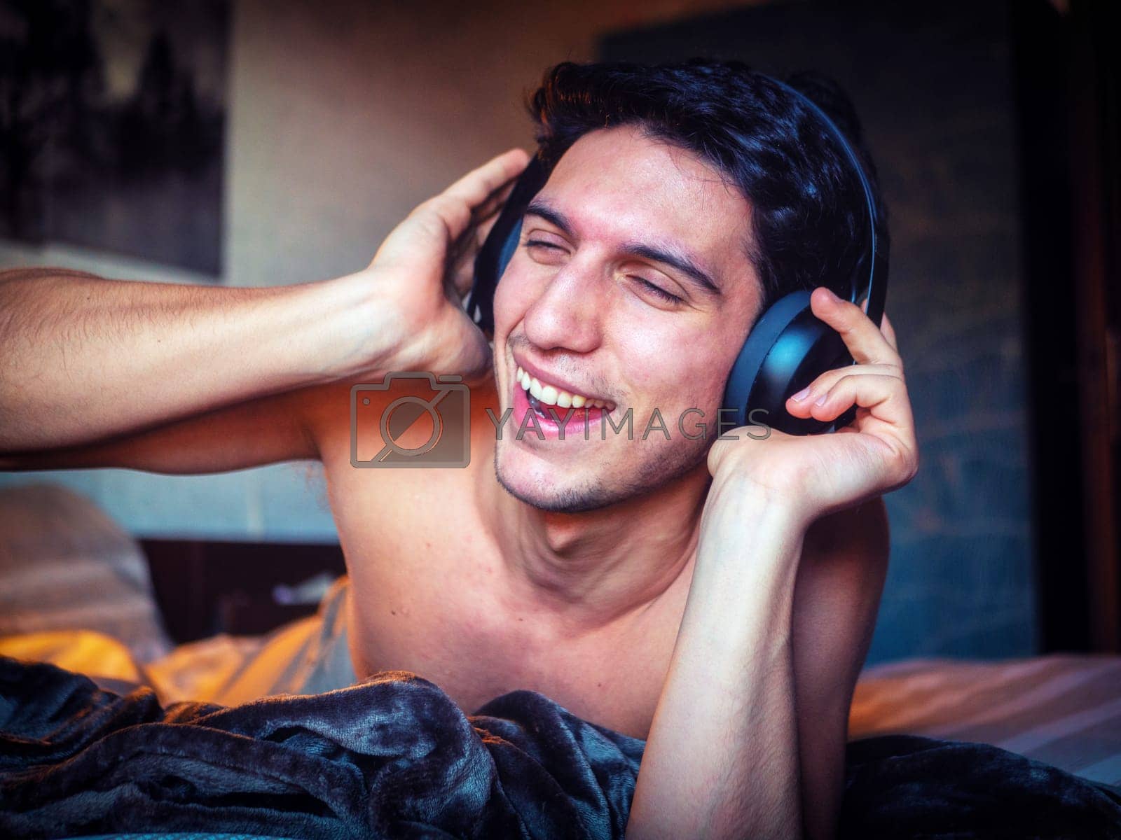 Royalty free image of Young Man Using Headphones Lying Alone On His Bed by artofphoto