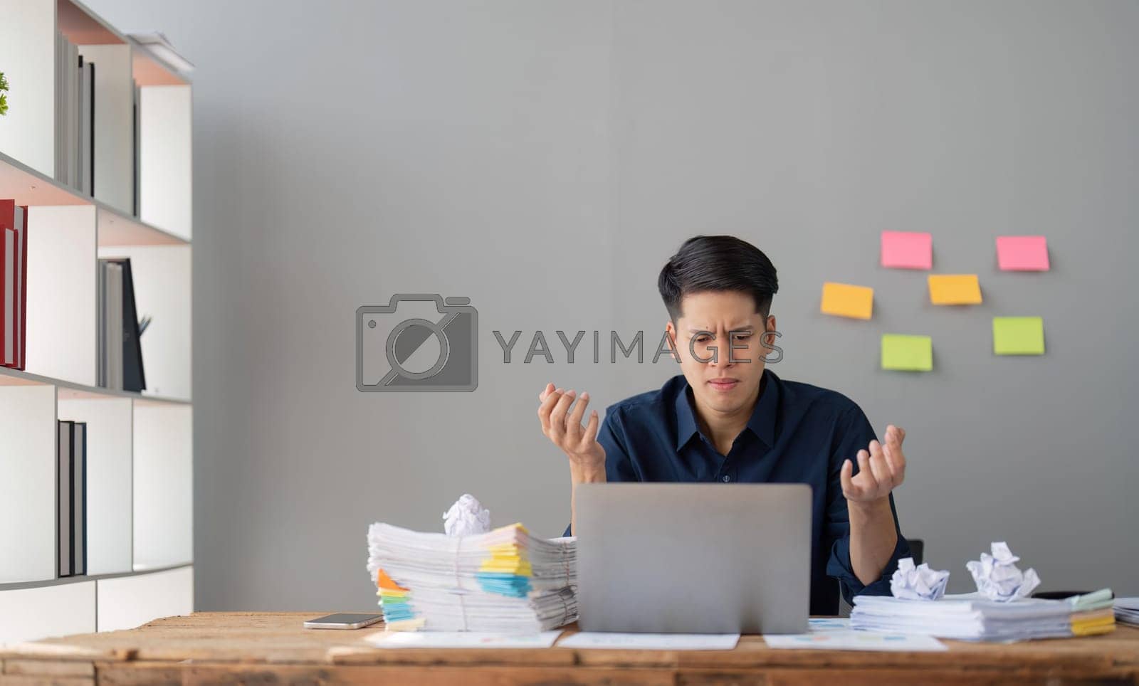 Royalty free image of Young stressed businessman working in office. Angry businessman with too much work in office by nateemee