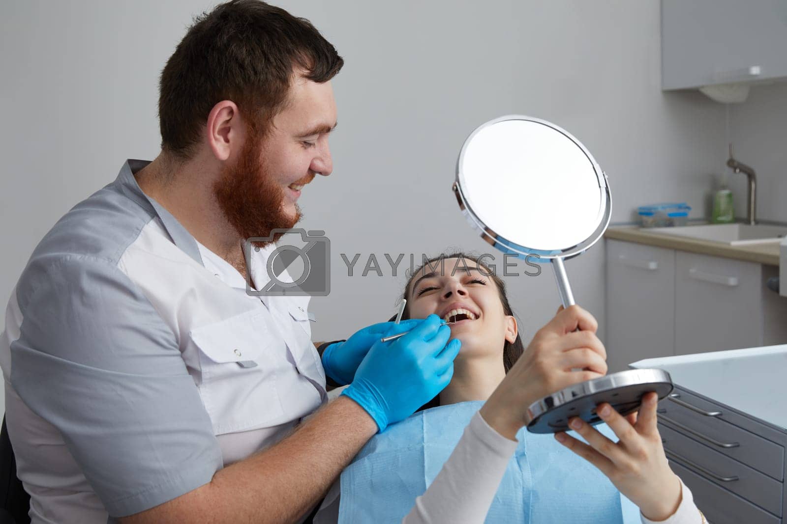 Royalty free image of Young Woman checking her beautiful smile in mirror after stomatological treatment by Mariakray