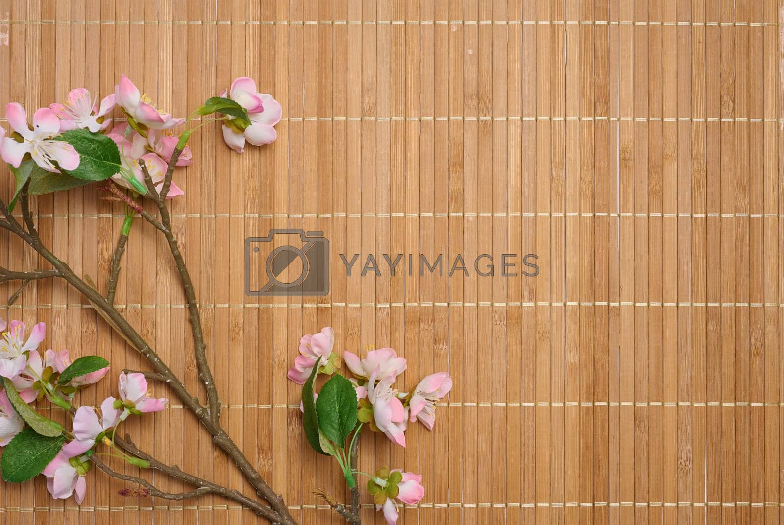 Royalty free image of A branch with textile cherry blossoms on a brown background, top view, by ndanko