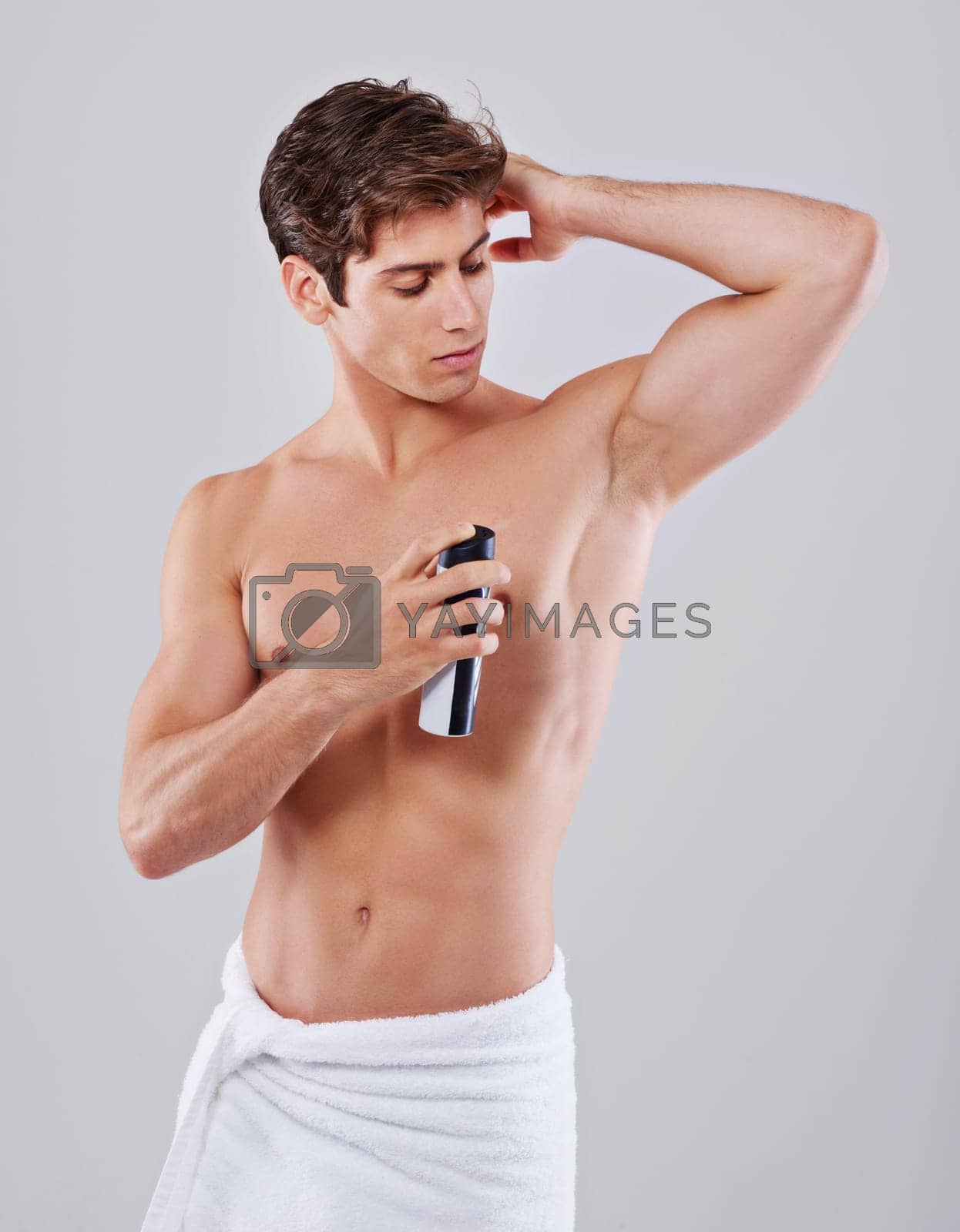 Royalty free image of The final grooming touch. Studio shot of a handsome bare chested young man spraying himself with deodorant. by YuriArcurs
