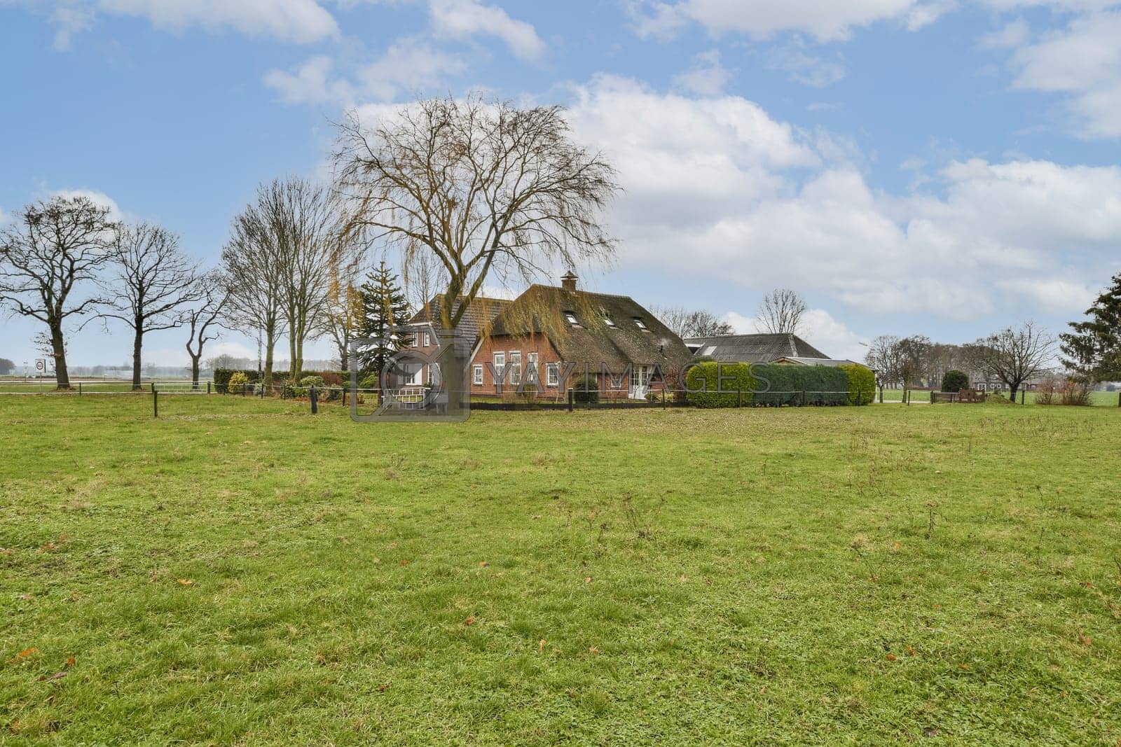 Royalty free image of a farm house in a field with a blue sky by casamedia