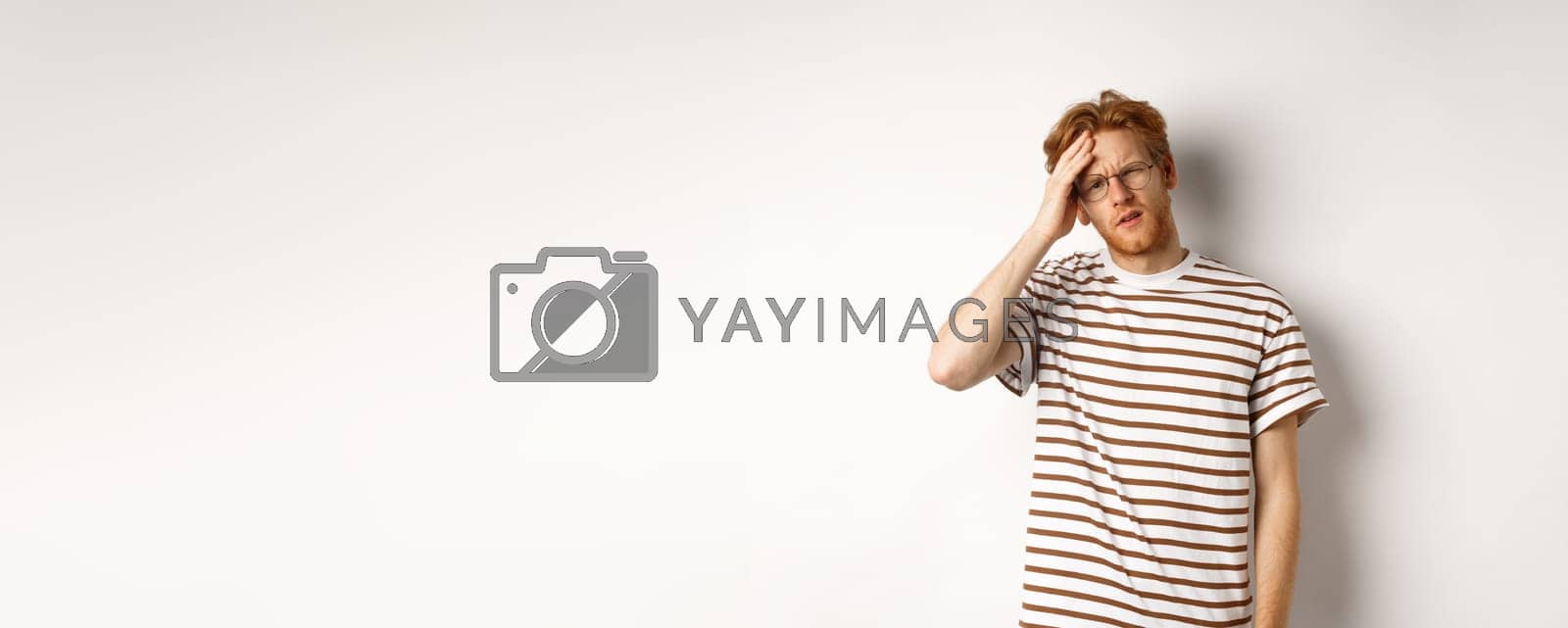 Royalty free image of Tired young man student touching head, looking complex and tired, standing over white background by Benzoix