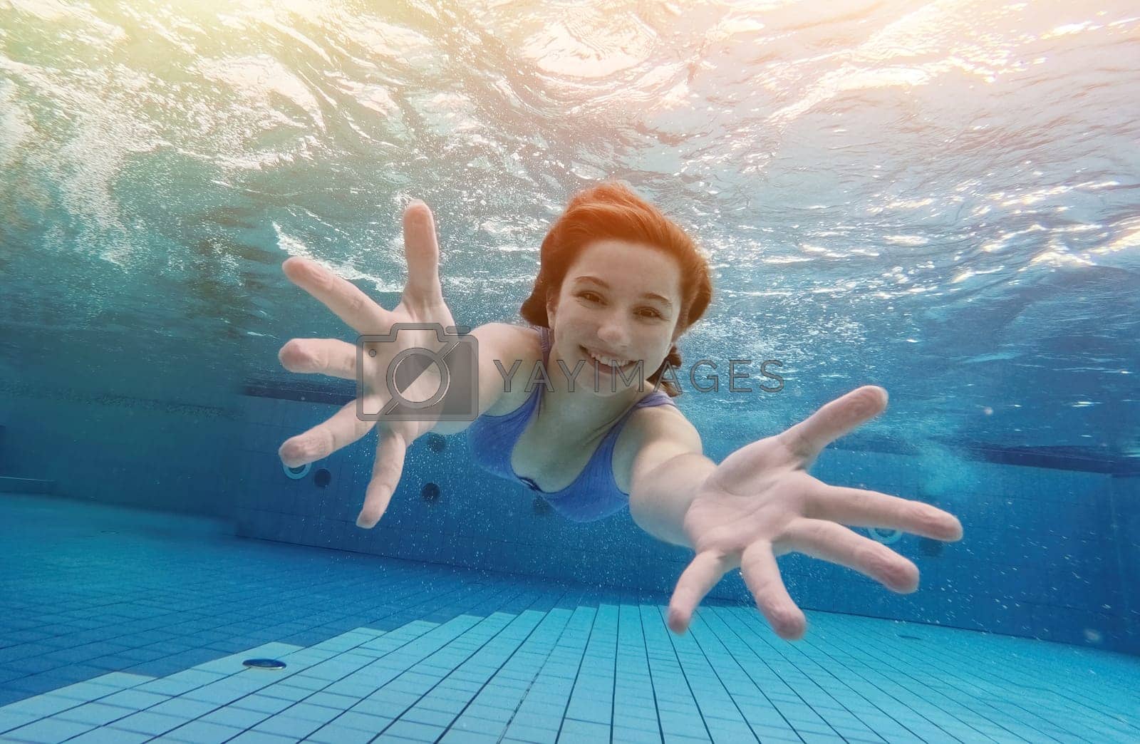 Royalty free image of Teen girl swimming under water in blue pool by GekaSkr