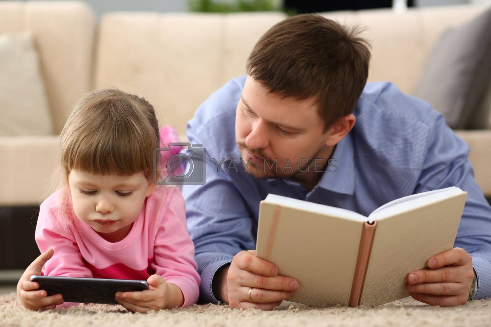 No more communication in family and dependence of children on gadgets. Dad holding book child is staring at smartphone screen