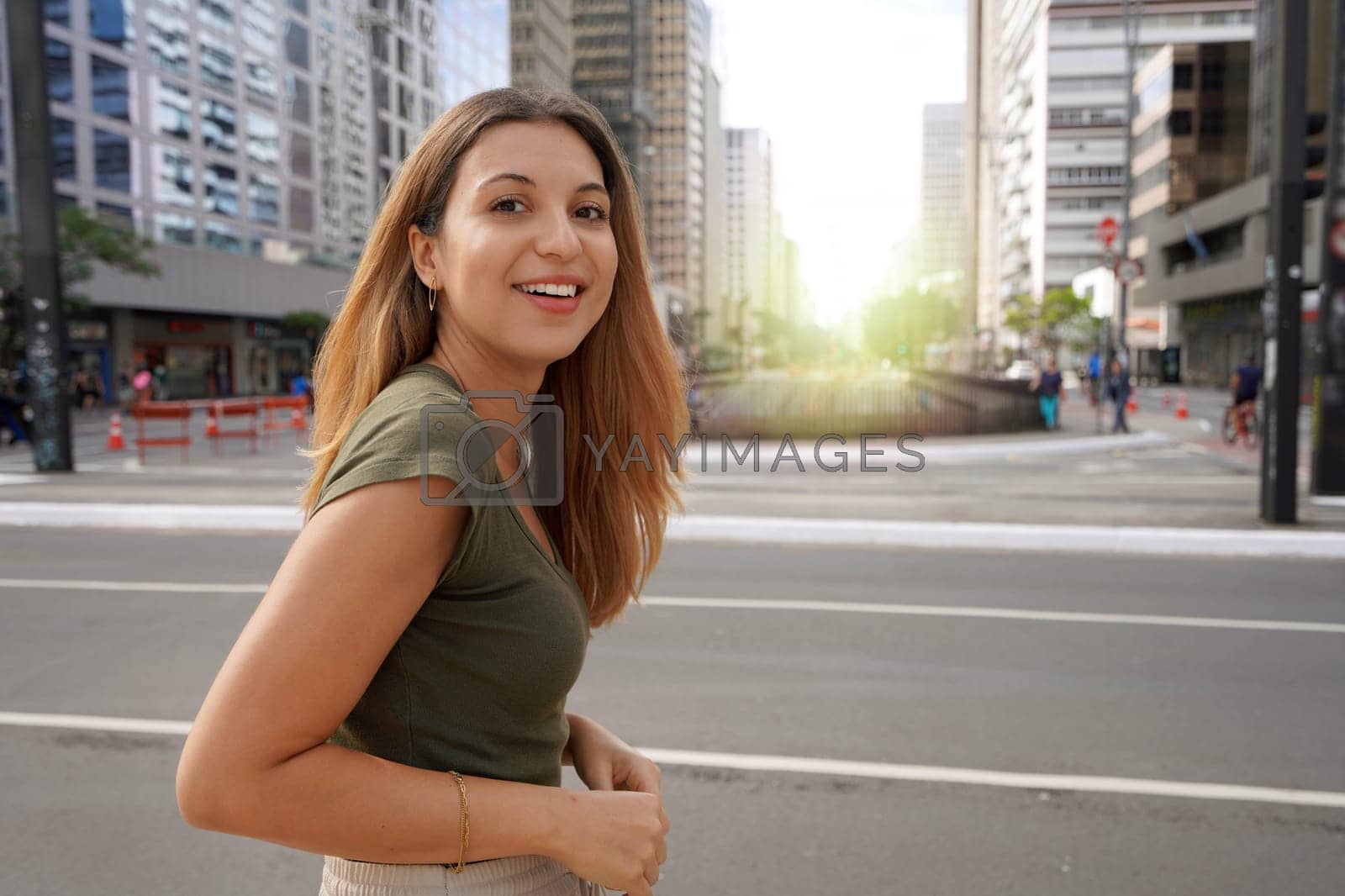 Royalty free image of Brazilian self-confident young woman smiling at camera with Paulista Avenue on the background in the morning, Sao Paulo, Brazil by sergio_monti