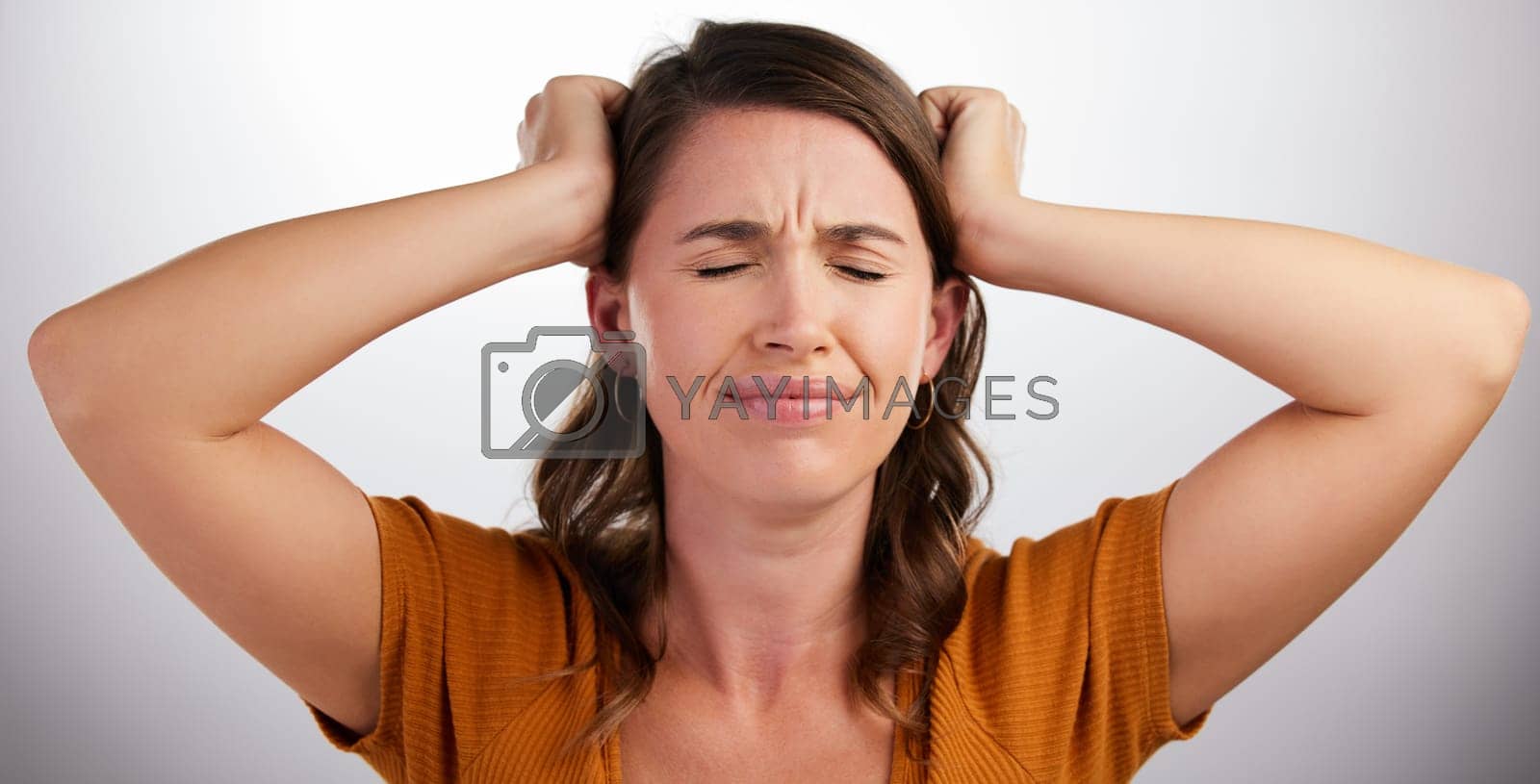 Royalty free image of Frustration is on 100. Studio shot of a young woman holding her head against a white background. by YuriArcurs
