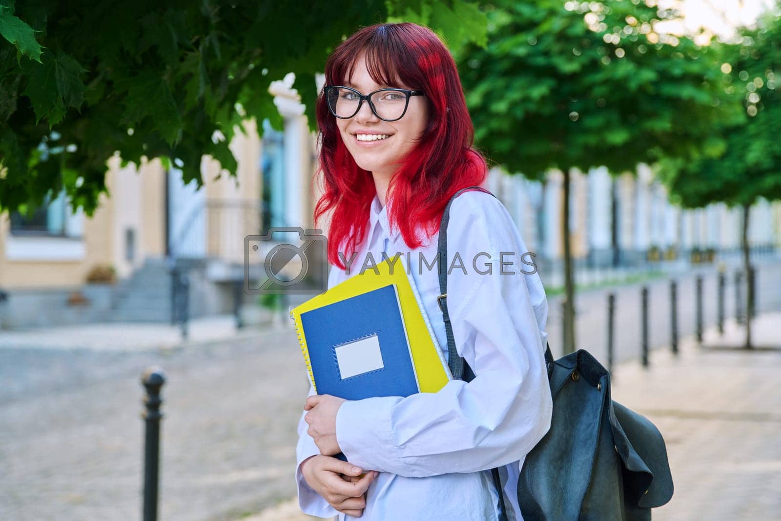 Royalty free image of Portrait of smiling female student 18, 19 years old on city street by VH-studio