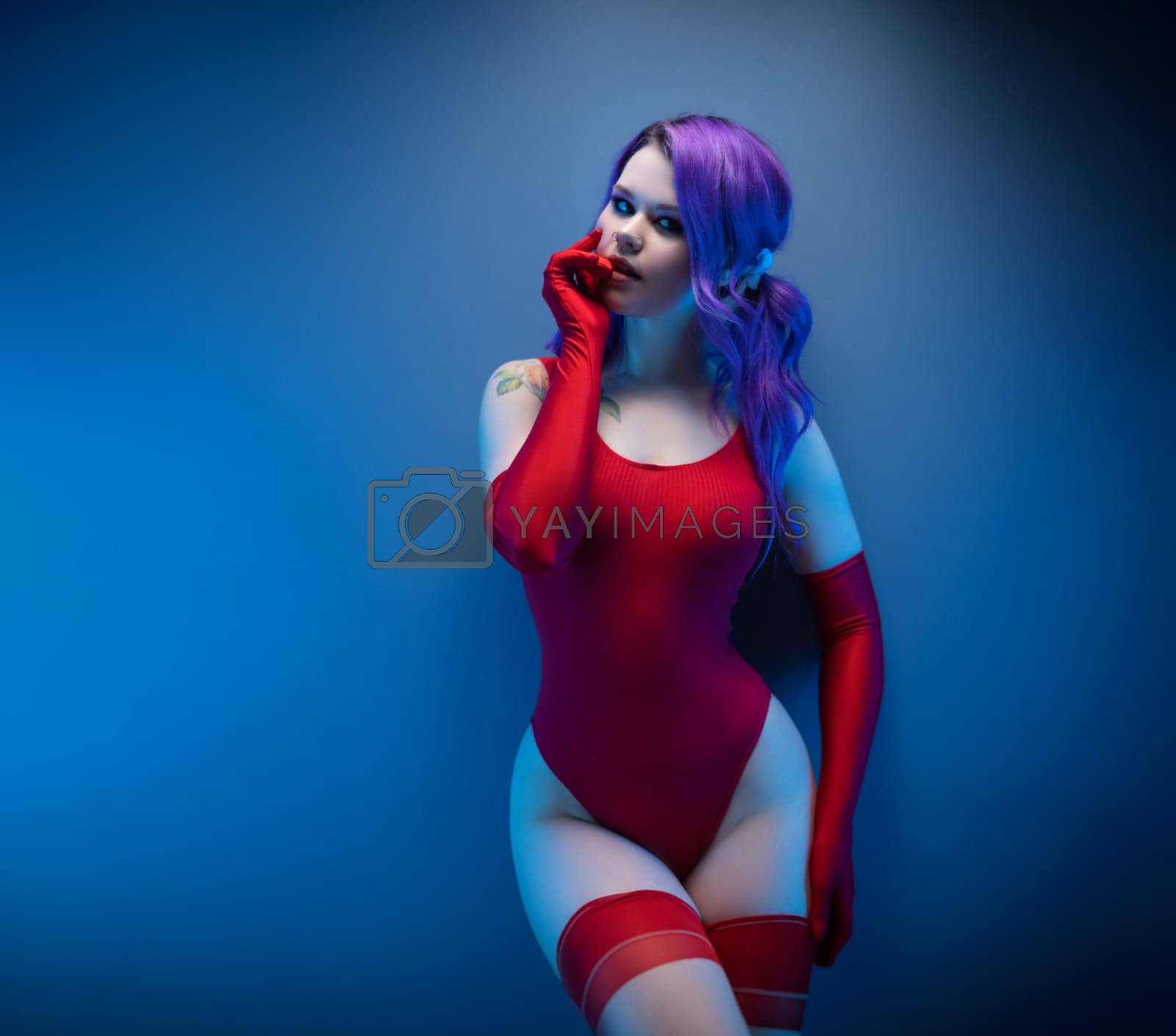 Royalty free image of sexy girl in red bodysuit stockings and red gloves poses erotically against the background by Rotozey