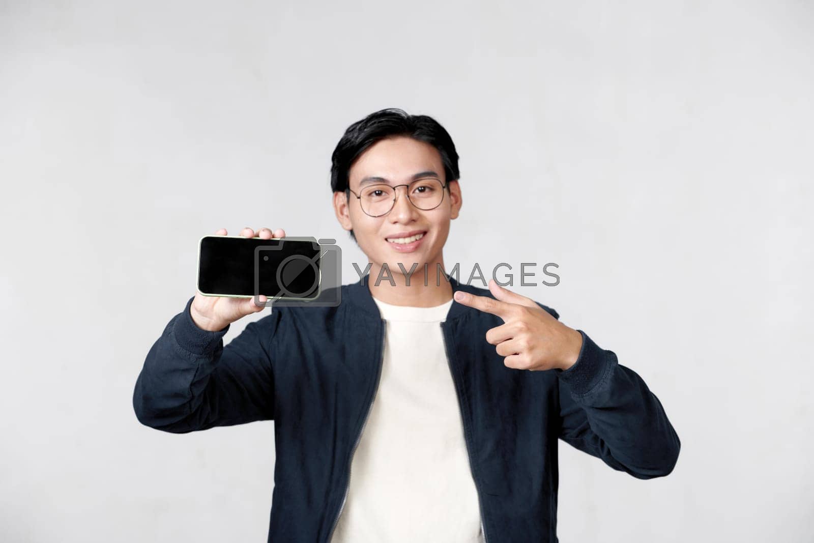Royalty free image of Young man holding smartphone in his hand and pointing his finger on blank screen by makidotvn