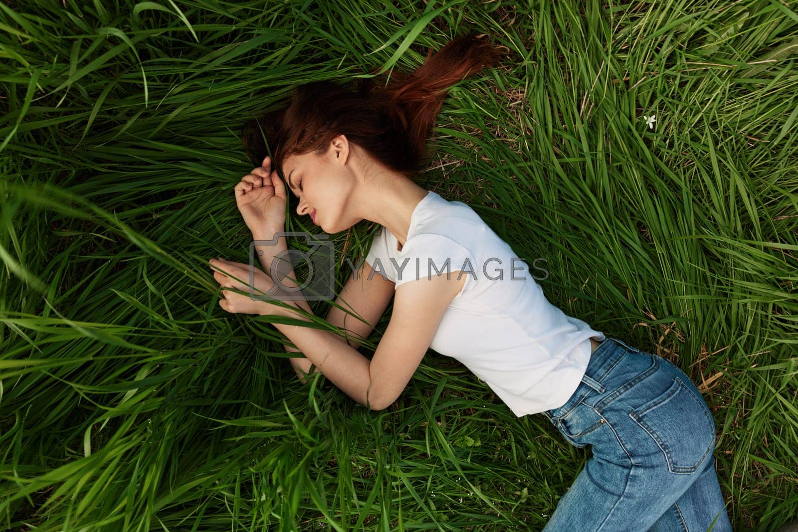 Royalty free image of woman lies in tall grass falling asleep in nature by Vichizh