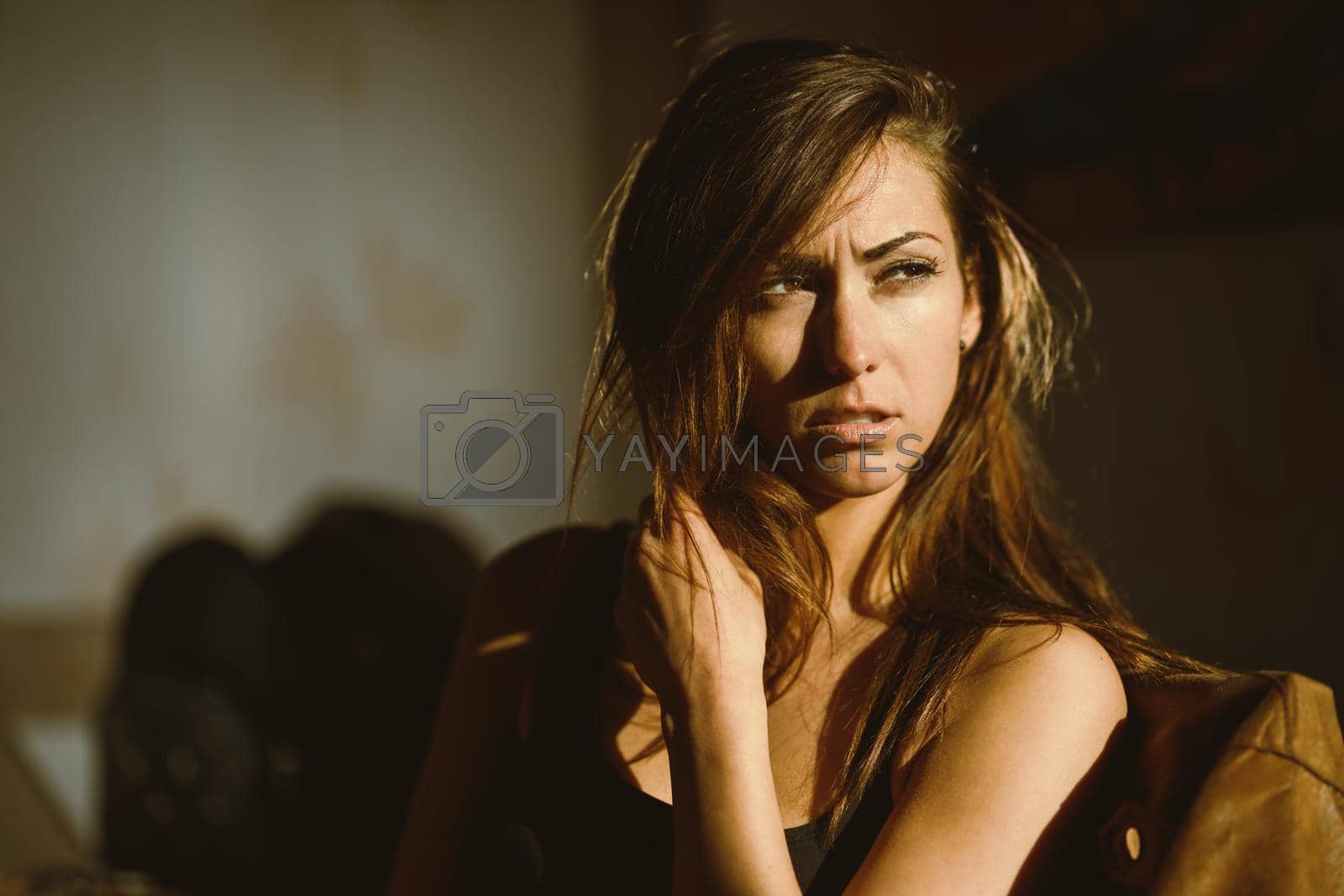 An attractive pensive woman sitting and frowning looking away a sunny morning.
