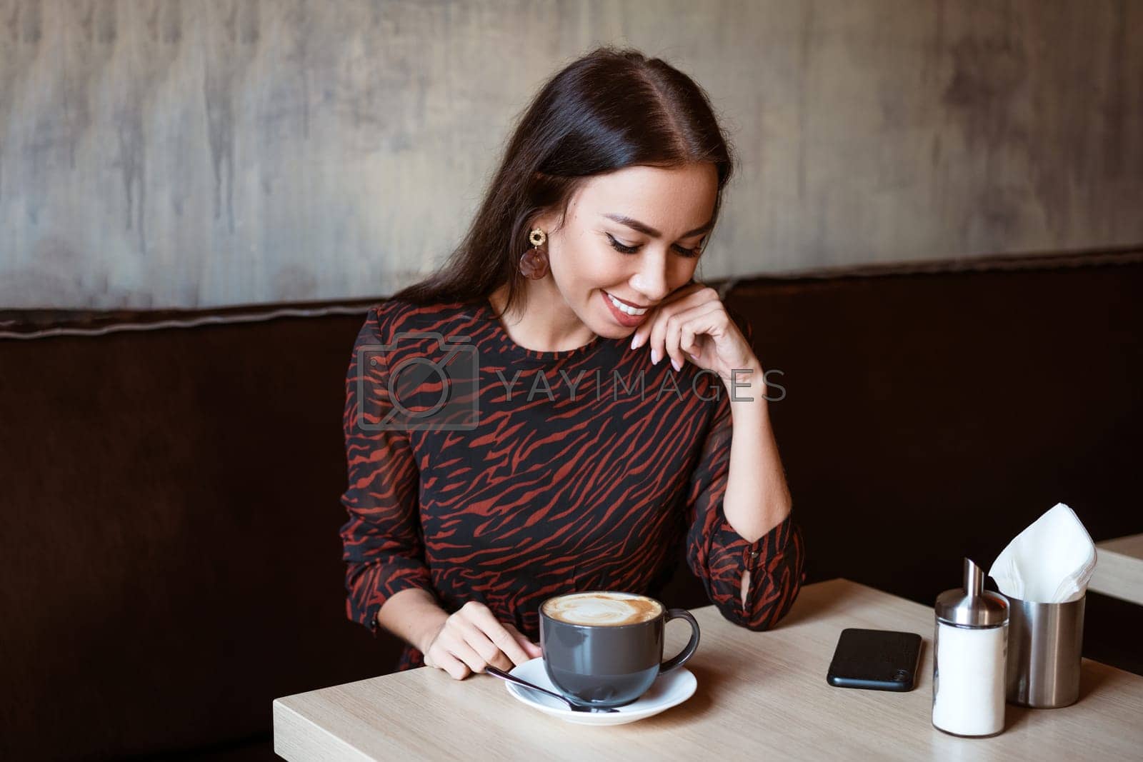 Royalty free image of Cheerful girl at a table in a cafe with a cup of coffee by EkaterinaPereslavtseva