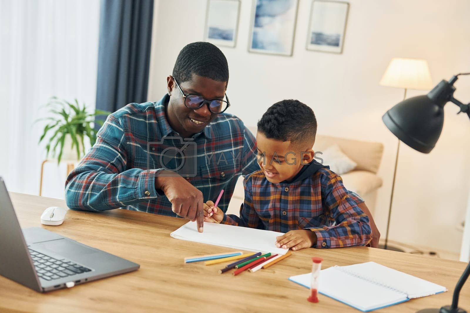 Royalty free image of Drawing together. African american father with his young son at home by Standret