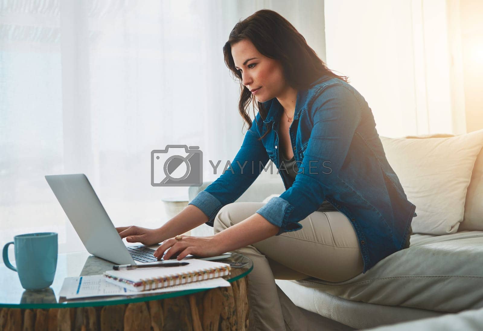Royalty free image of Keeping her blog relevant. an attractive young woman using her laptop at home. by YuriArcurs