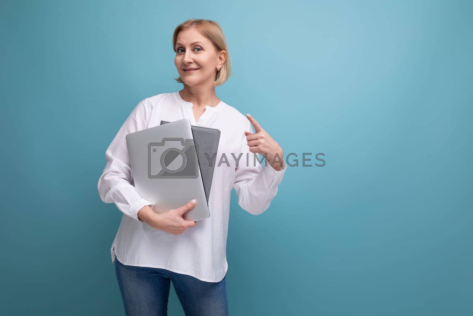 Royalty free image of serious adult woman with blond hair working remotely using laptop by TRMK