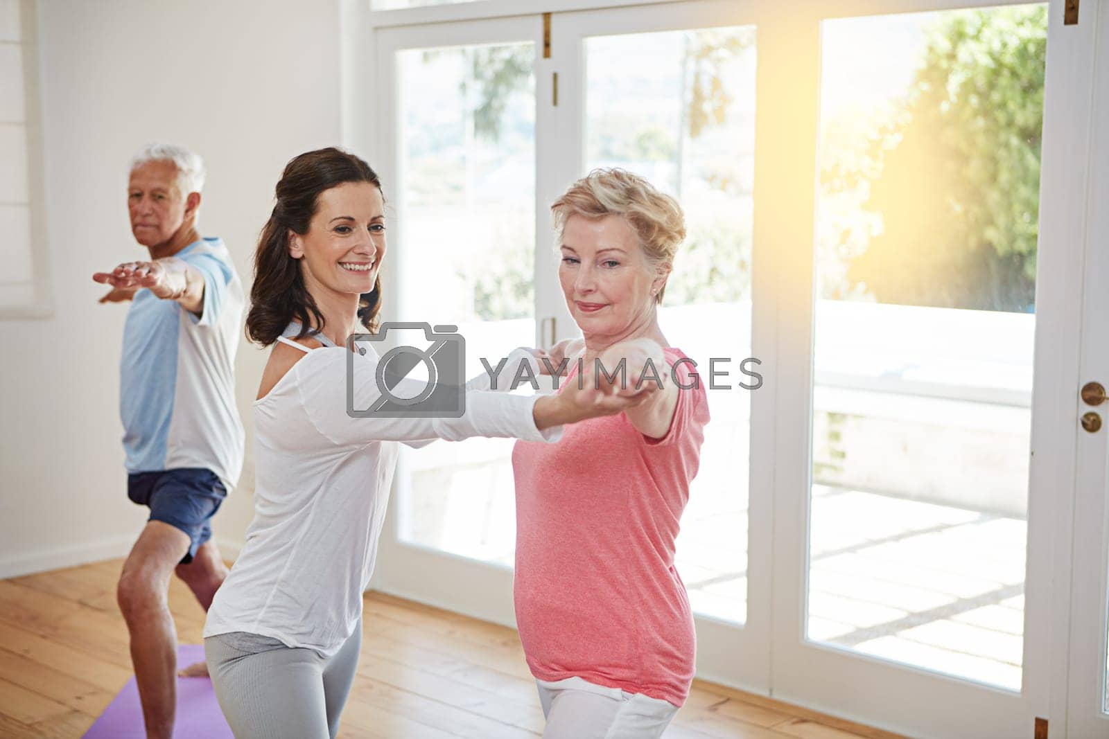 Royalty free image of Happy to work with seniors. a female yoga instructor working with a senior couple. by YuriArcurs