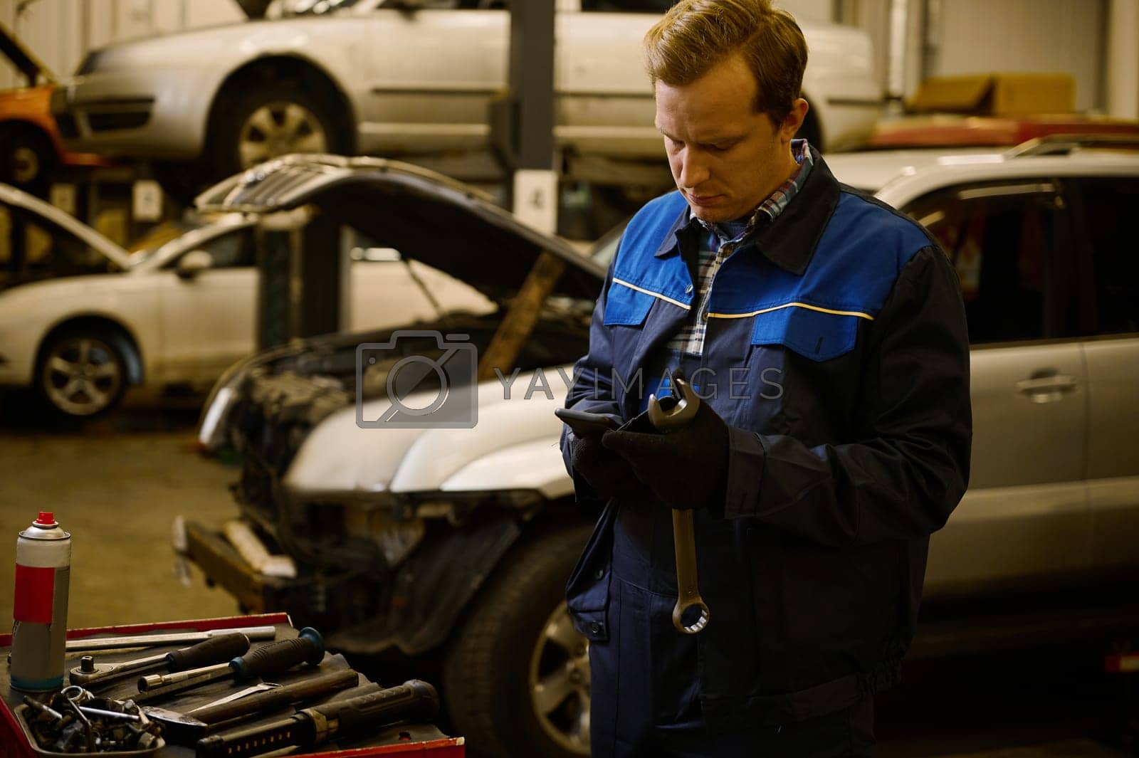 Royalty free image of Technician, mechanic in professional uniform with wrench at repair shop. Automobile warranty repair and maintenance concept by artgf