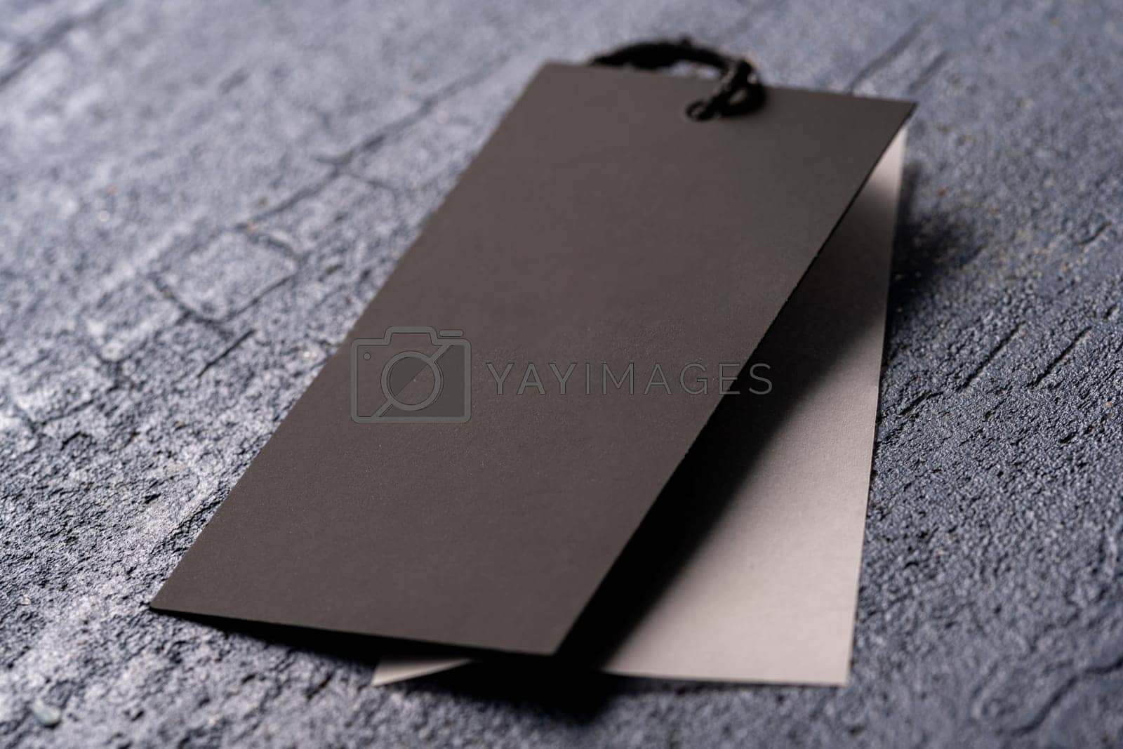 Royalty free image of A closeup shot of a blank black clothing tag on a string for a price label on a cloth by A_Karim