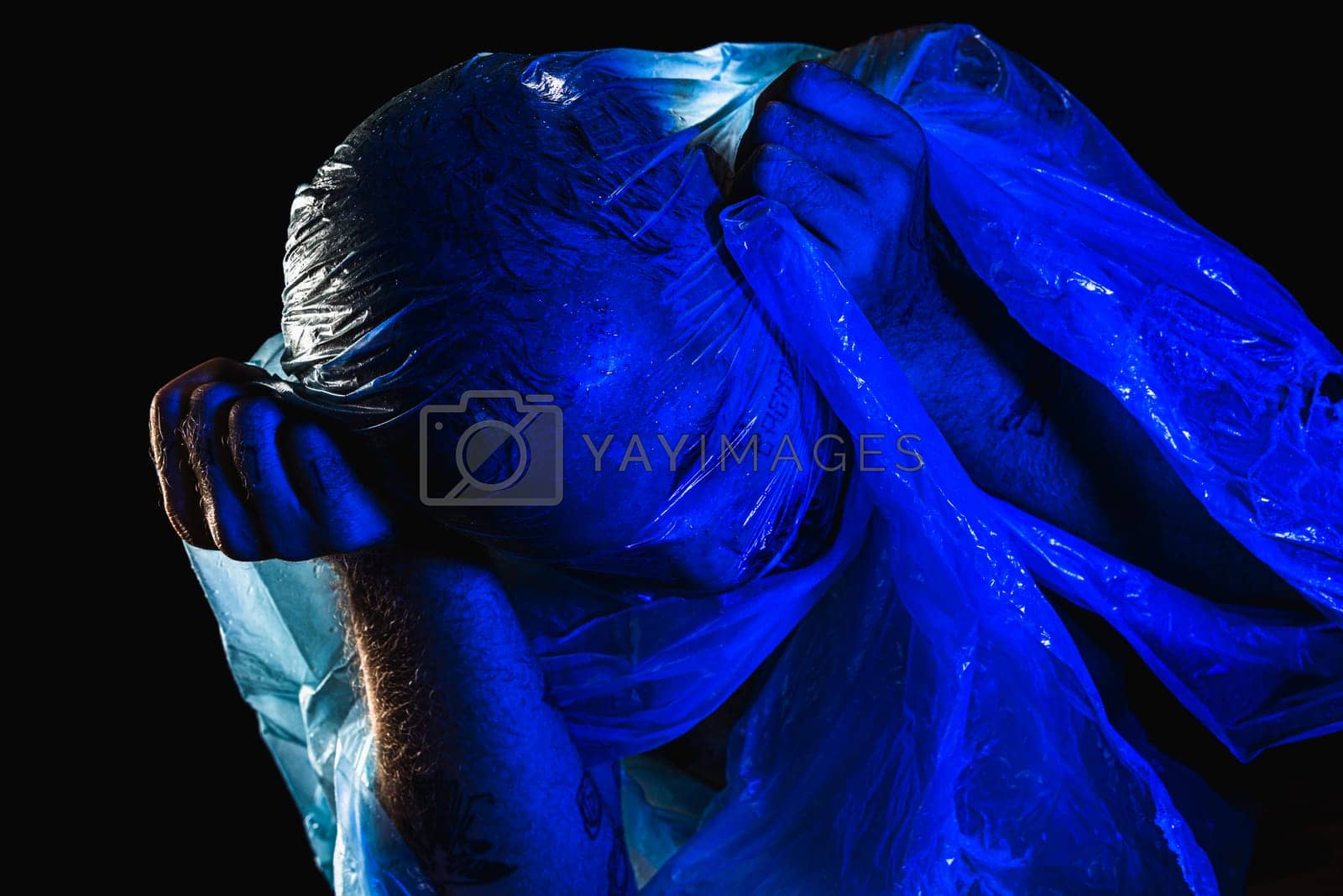 Royalty free image of Man with plastic bag over his head, suffocated. Studio shot with blue filter.  by ThalesAntonio
