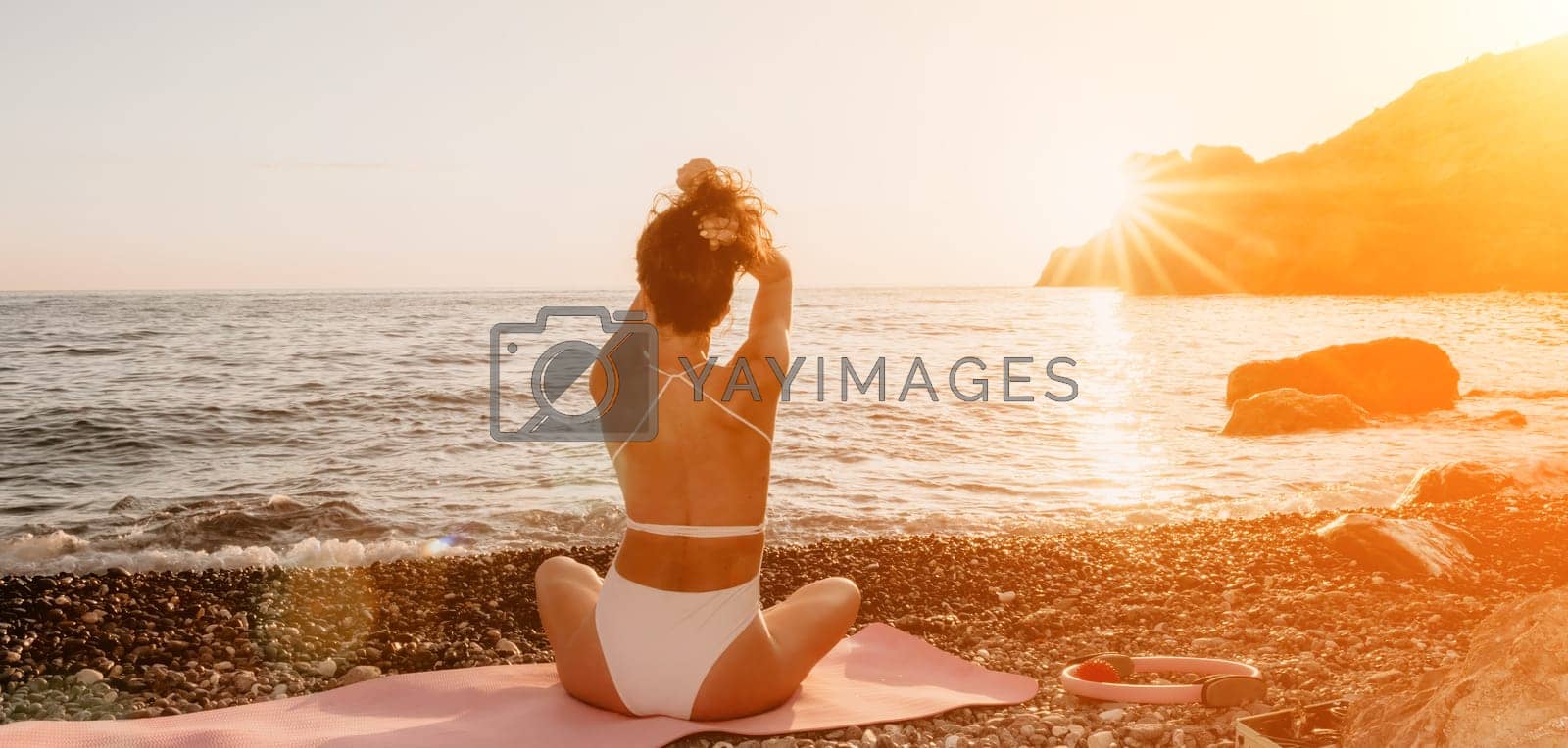 Royalty free image of Woman sea yoga. Happy woman in white swimsuit and boho style braclets practicing outdoors on yoga mat by sea on sunset. Women yoga fitness routine. Healthy lifestyle, harmony and meditation by panophotograph