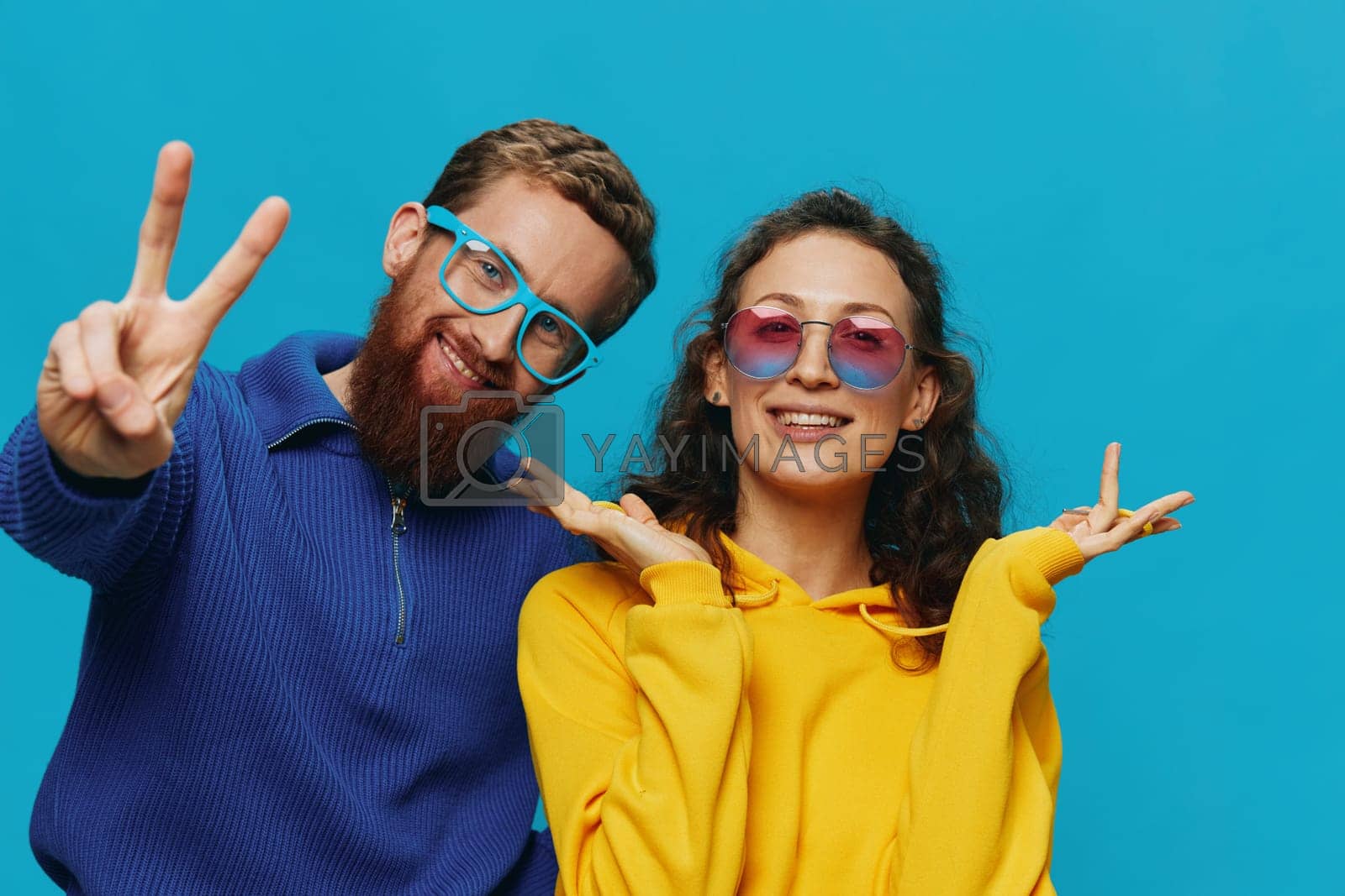 Royalty free image of A woman and a man fun couple cranking and showing signs with their hands smiling cheerfully, on a blue background, The concept of a real relationship in a family. by SHOTPRIME