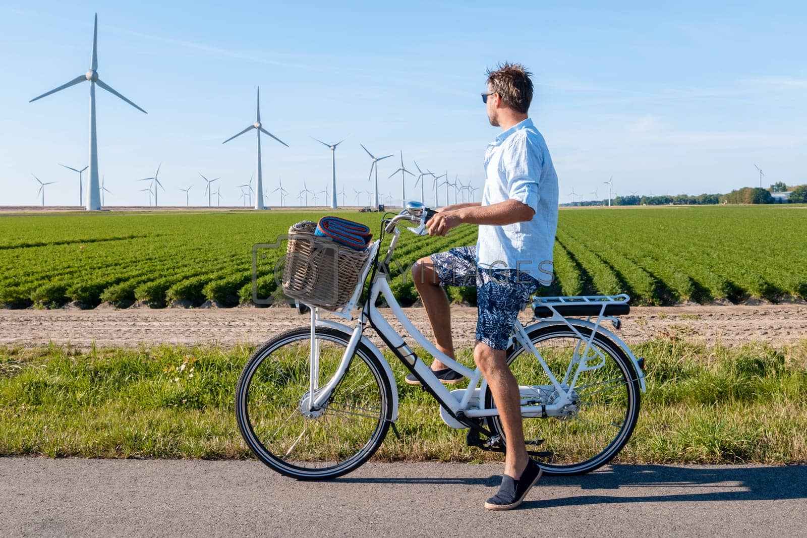 Royalty free image of young man electric green bike bicycle by windmill farm , windmills isolated on a beautiful summer by fokkebok