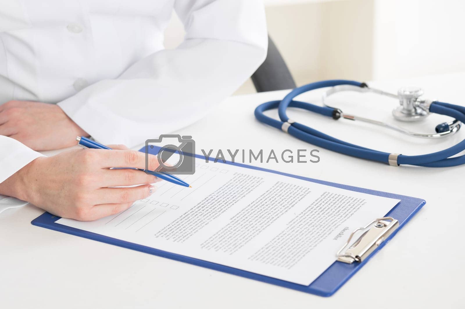 Royalty free image of Doctor writing on sheet in clipboard by Yellowj