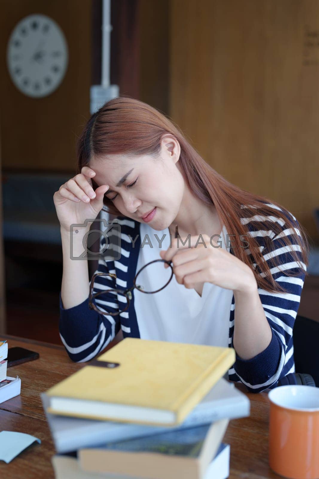 Royalty free image of A portrait of an Asian teenage girl showing headaches and discouragement from studying in the library by Manastrong