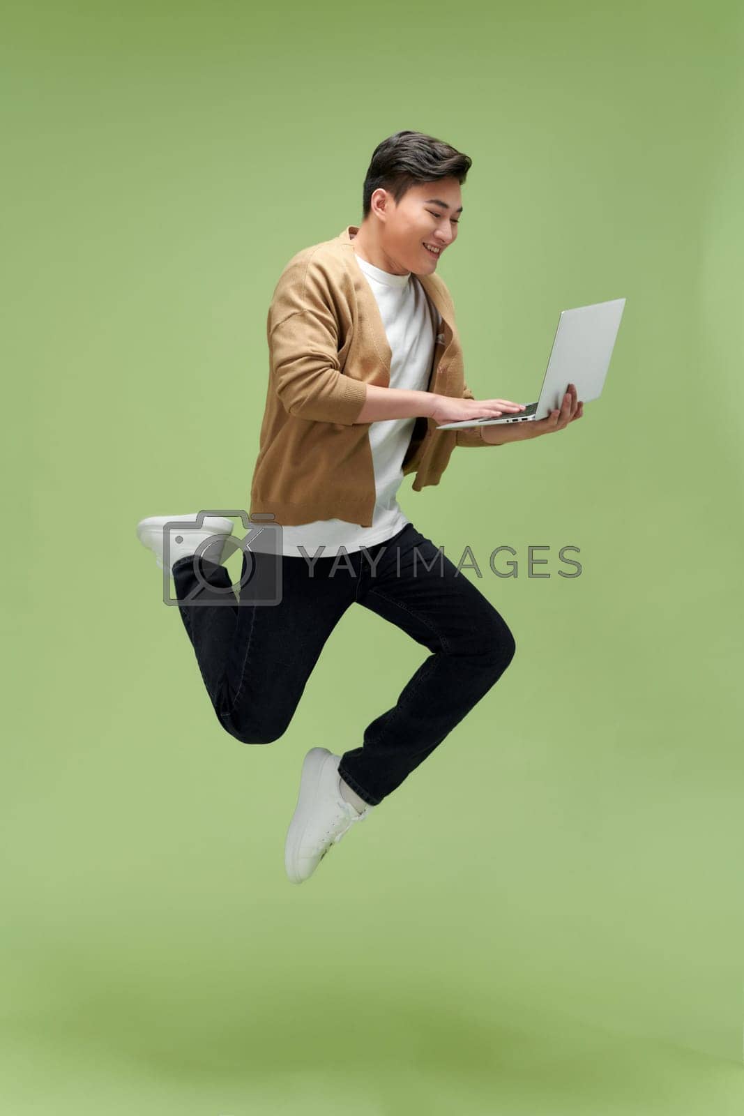 Royalty free image of Profile photo of sporty active guy jump hold netbook run work isolated green color background by makidotvn