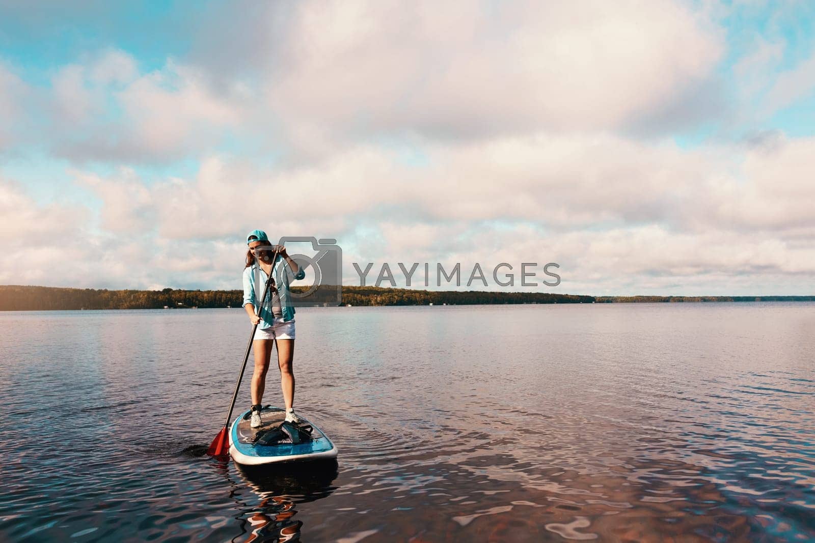 Royalty free image of Youll never know until you go. a young woman paddle boarding on a lake. by YuriArcurs