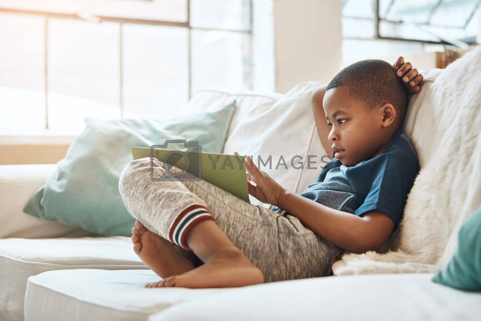 Royalty free image of Reading is dreaming with open eyes. a little boy reading a book at home. by YuriArcurs