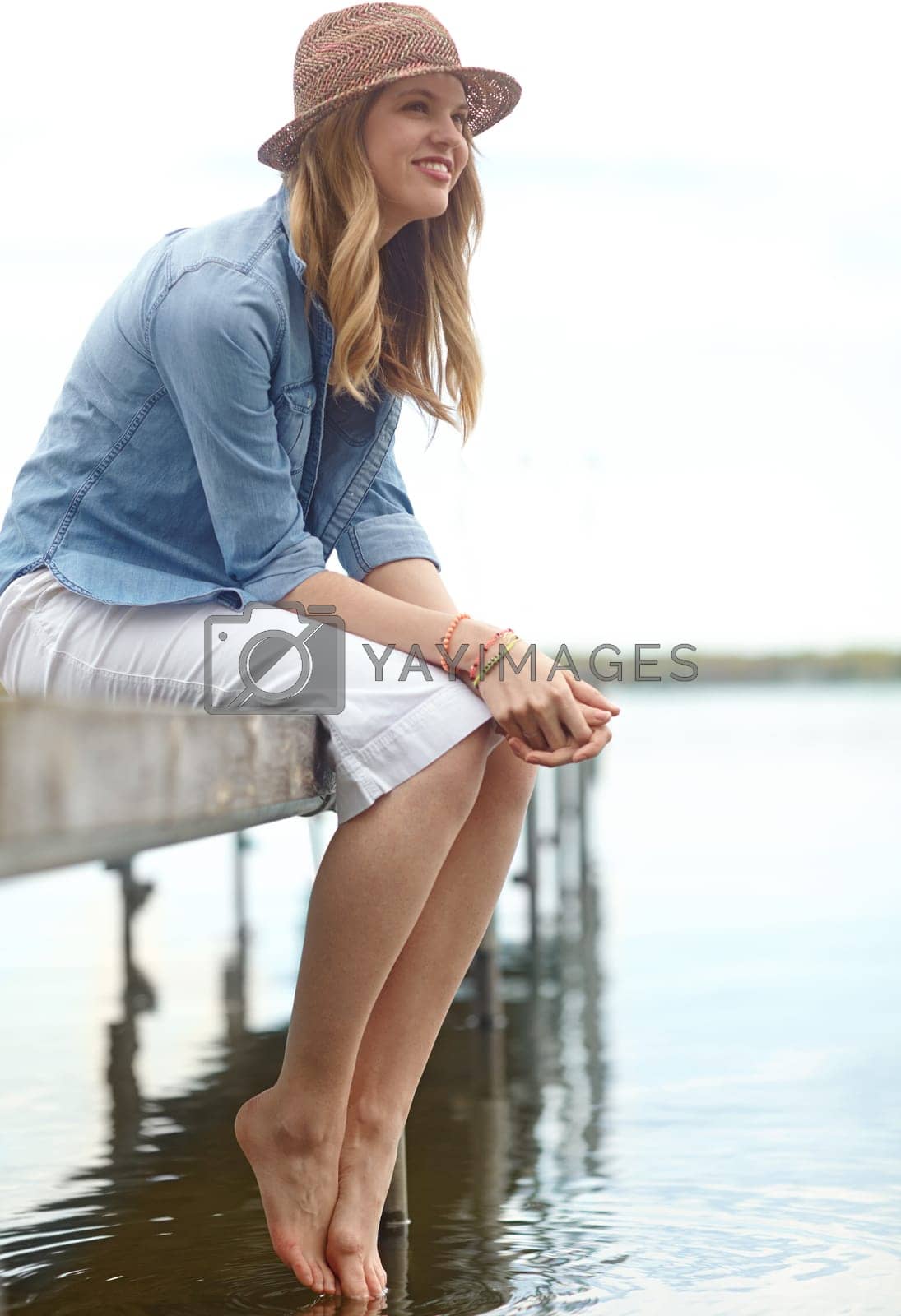 Royalty free image of Let your mind wander...A happy young woman sitting on a jetty next to a lake. by YuriArcurs