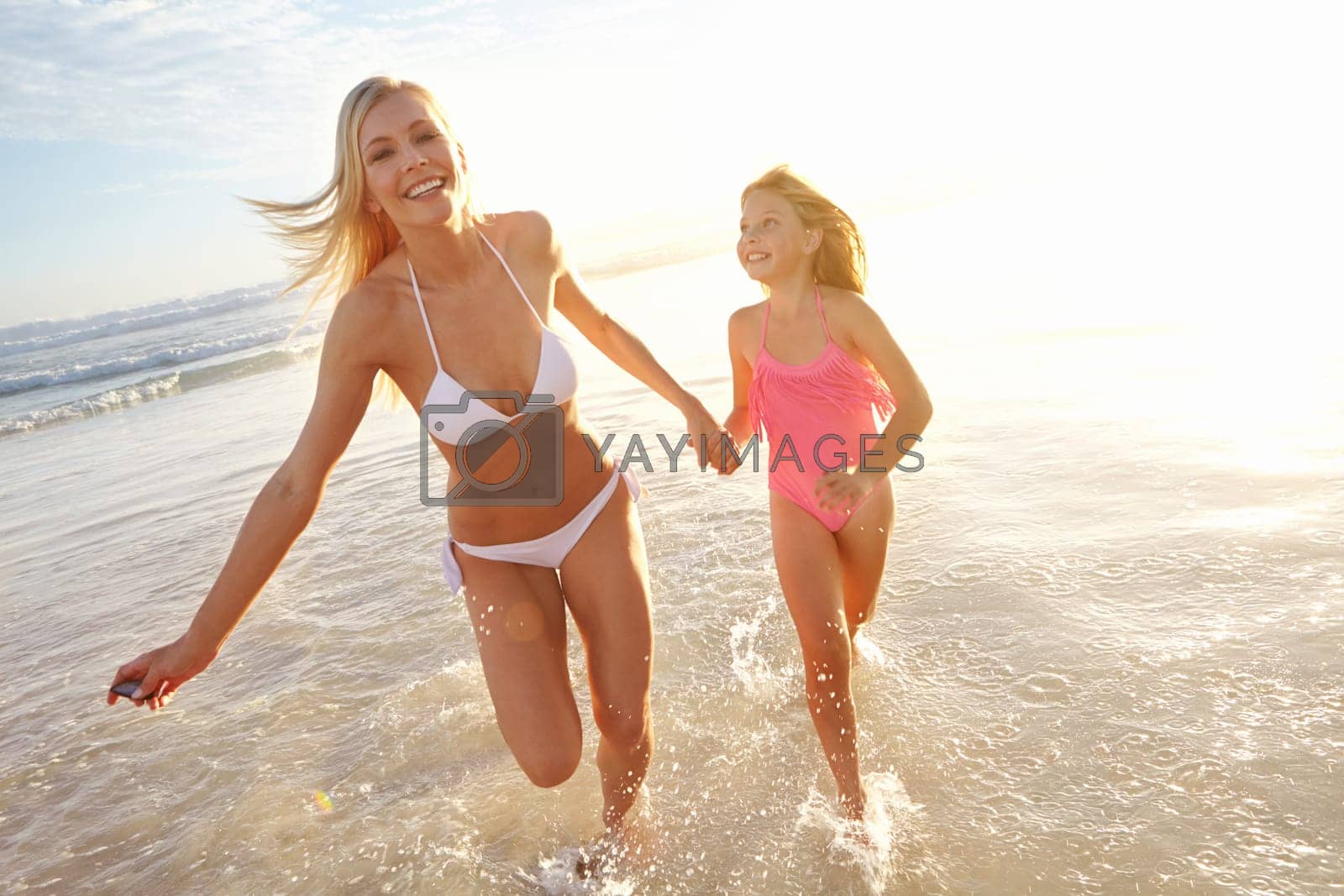Royalty free image of Running along the beach with mom. a young mother and her daughter running through shallow water on the beach. by YuriArcurs