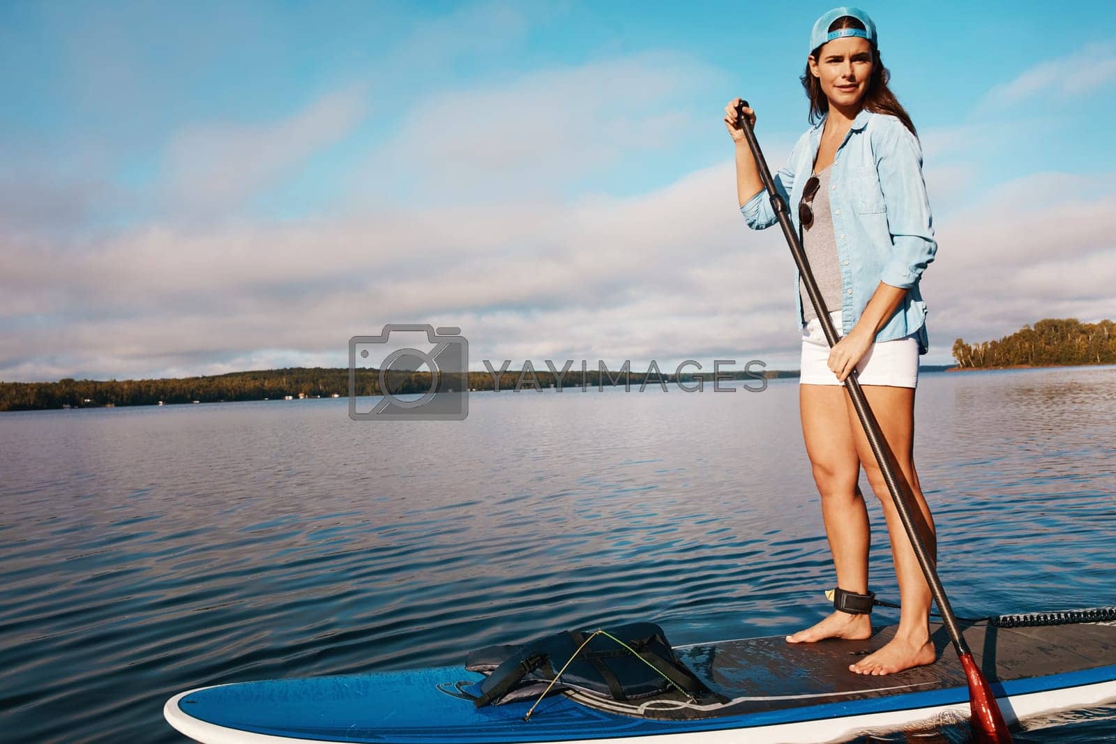 Royalty free image of Having some fun out on the water. a young woman paddle boarding on a lake. by YuriArcurs