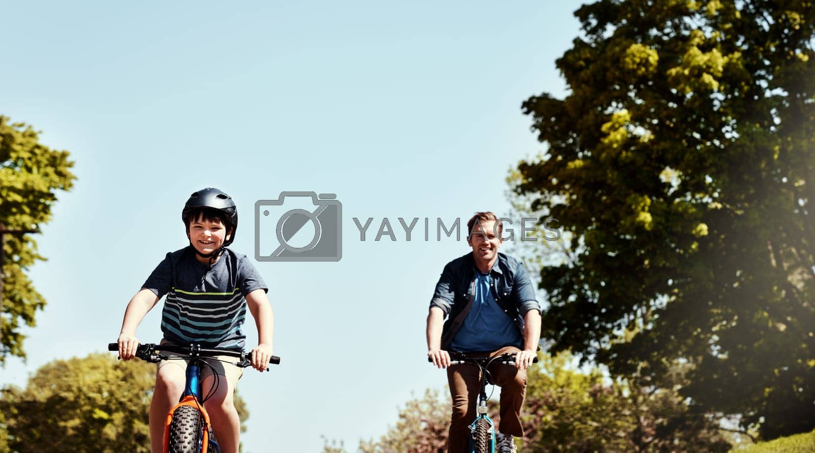 Royalty free image of Its their fun activity to do together. a young boy and his father riding together on their bicycles. by YuriArcurs