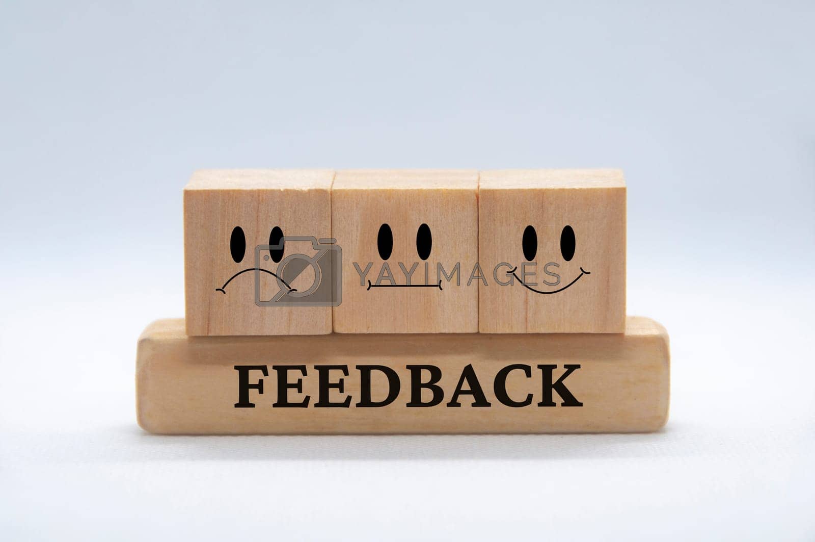Royalty free image of Sad, neutral and happy emotion faces on wooden cubes with white background cover. Customer feedback and evaluation concept. by yom98