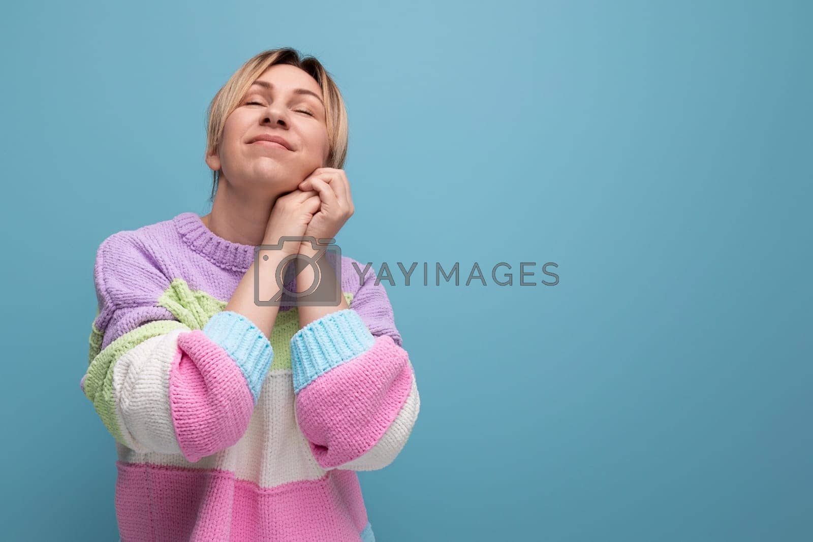 Royalty free image of dreamy blond woman in casual outfit on blue background with copy space by TRMK