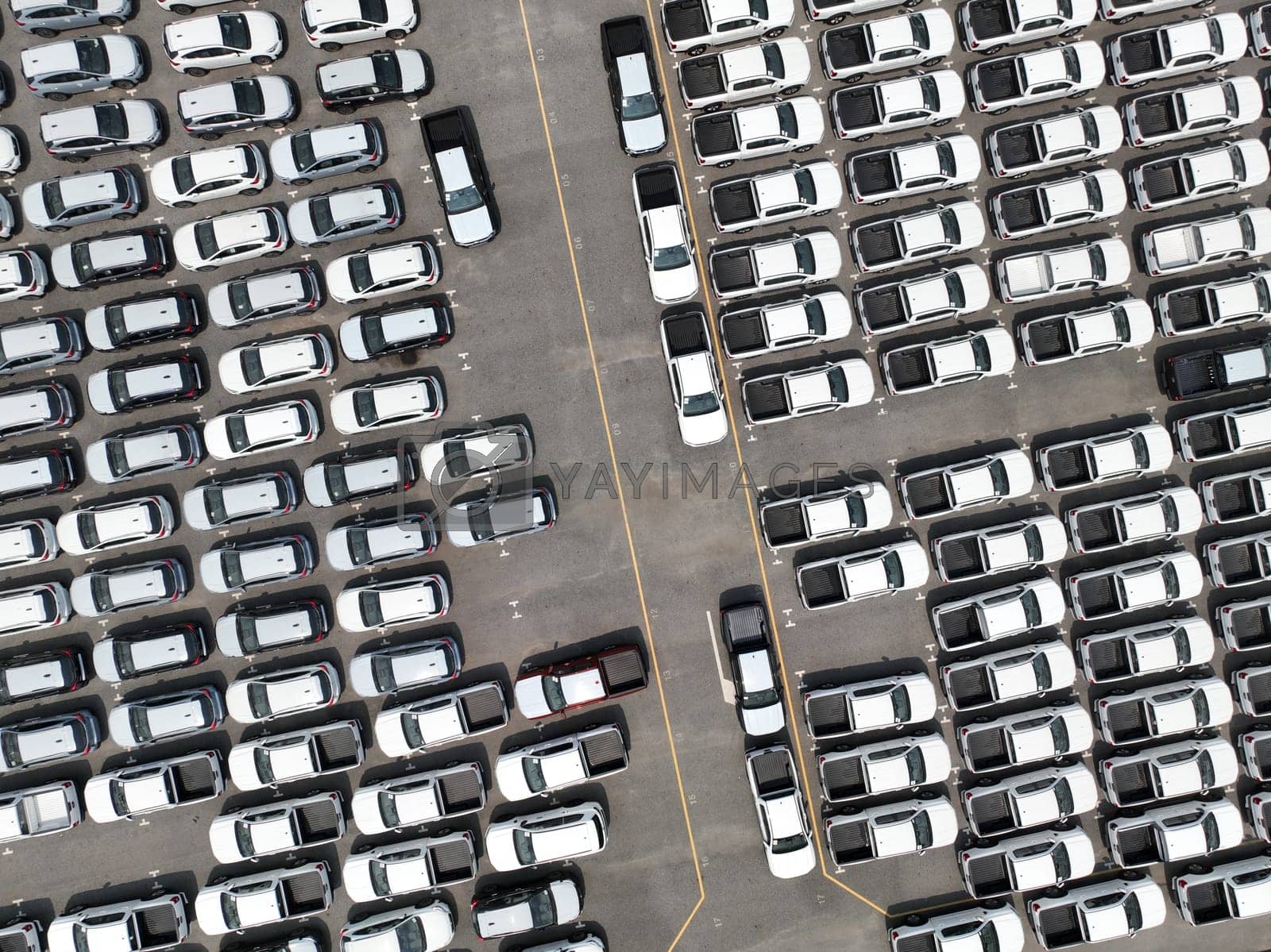 Royalty free image of Aerial view of new cars stock at factory parking lot. Above view cars parked in a row. Automotive industry. Logistics business. Import or export new cars at warehouse. Big parking lot at port terminal by Fahroni