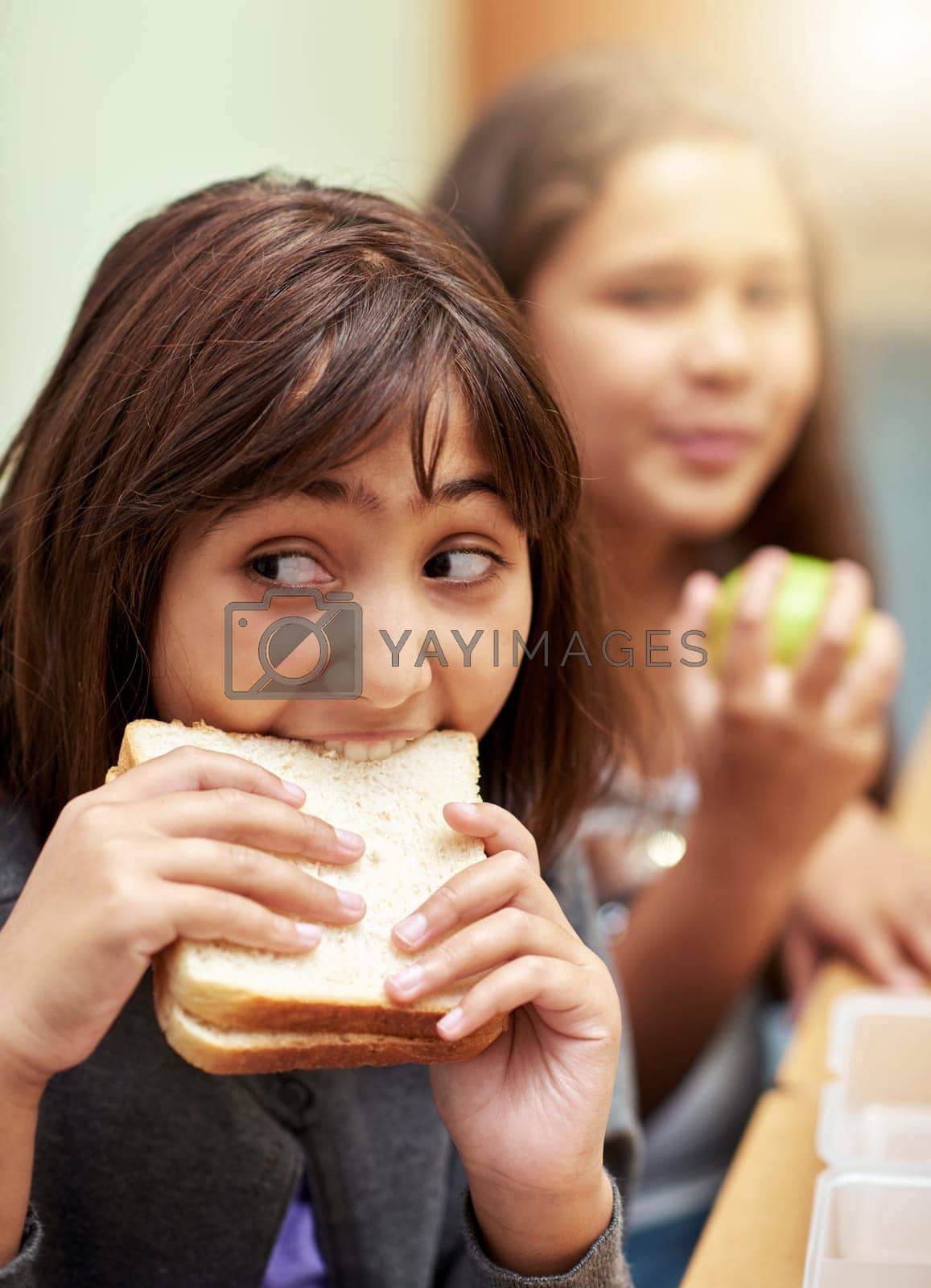 Royalty free image of Eating quickly to beat the bell. young school children eating lunch at school. by YuriArcurs